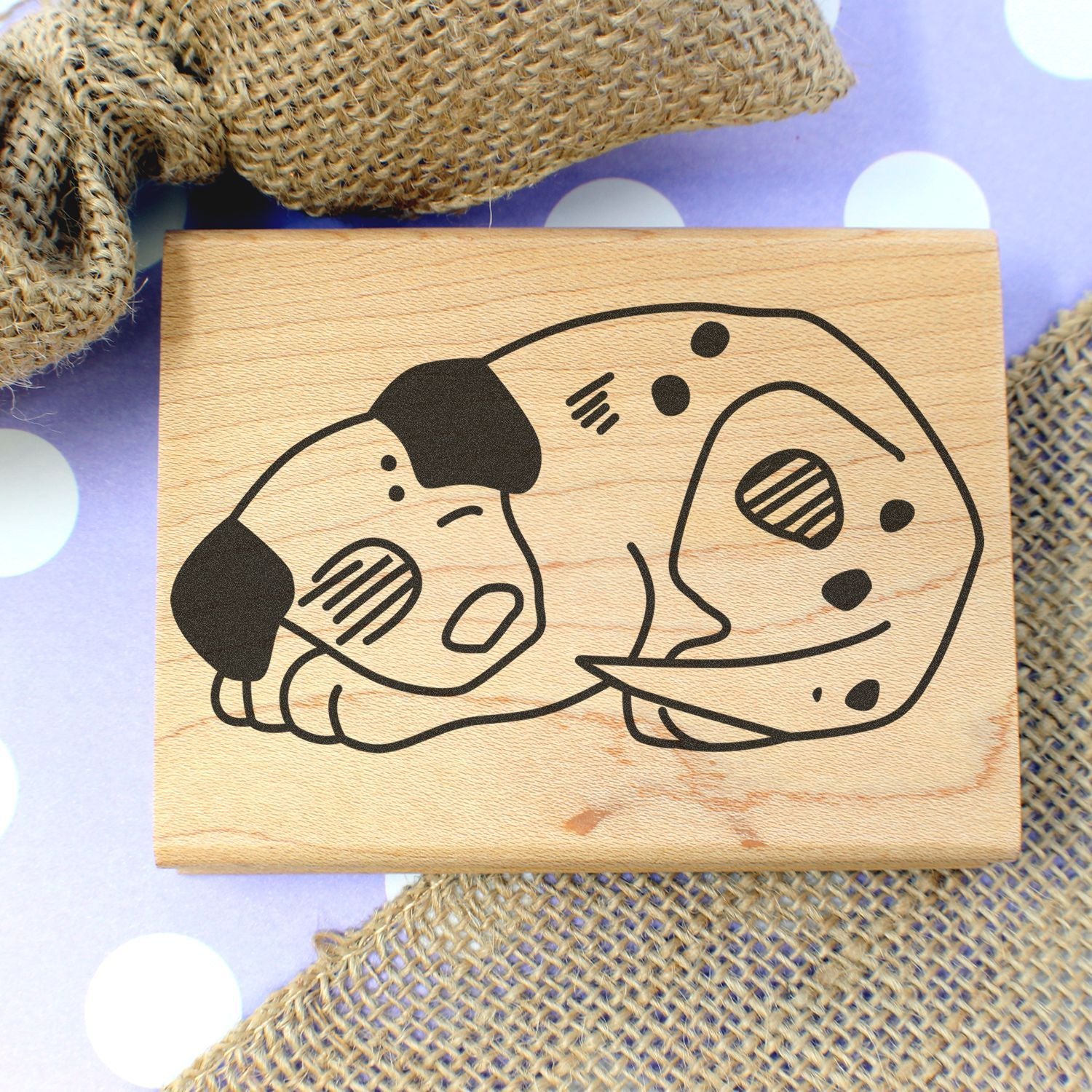 Wooden dog stamp with sleeping puppy illustration on rustic burlap background.