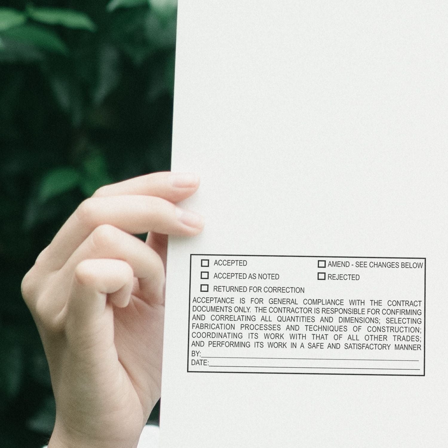 Hand holding a construction approval document with checklist boxes for accepted, rejected, and returned for correction.
