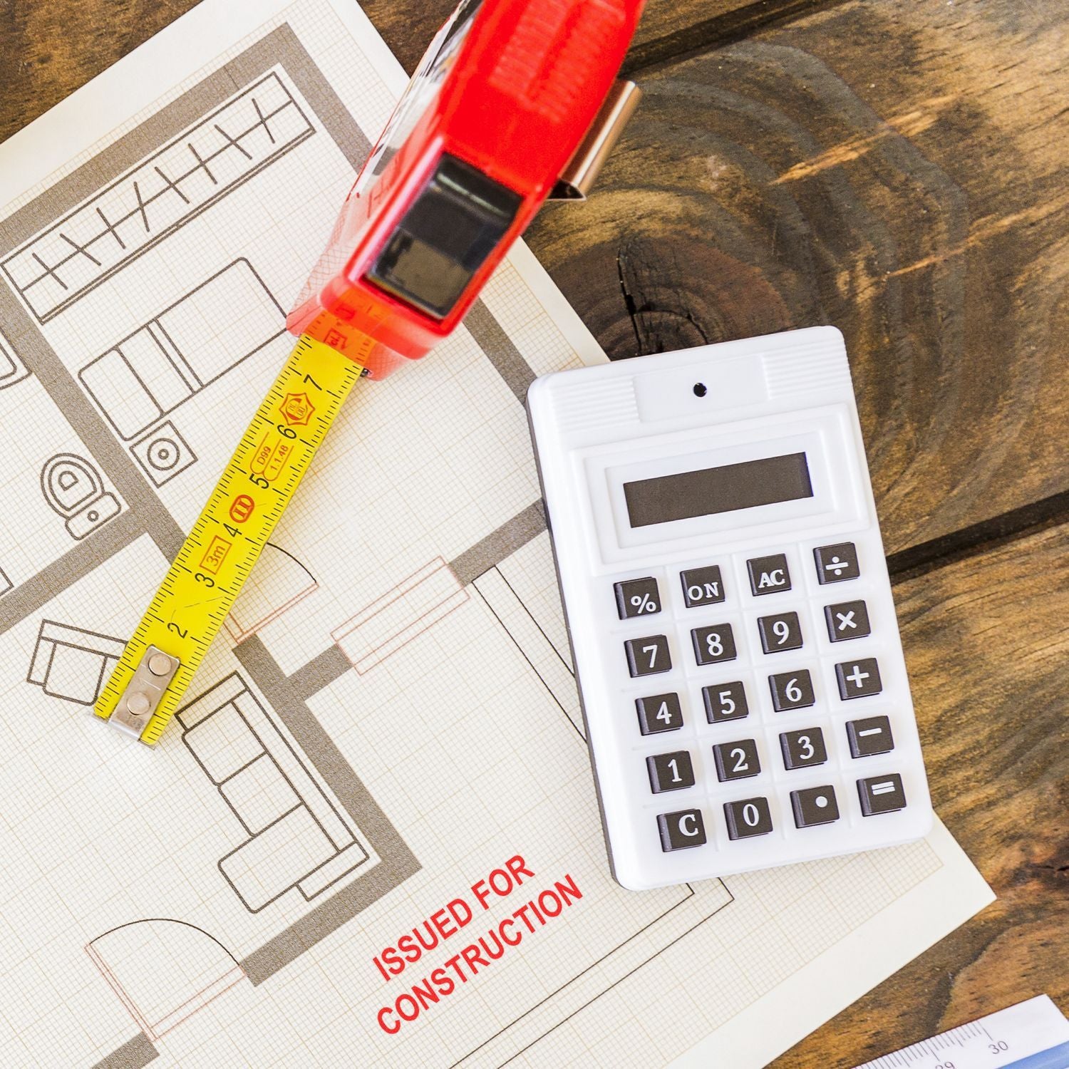 Construction blueprint with tape measure and calculator for home renovation estimating and planning.