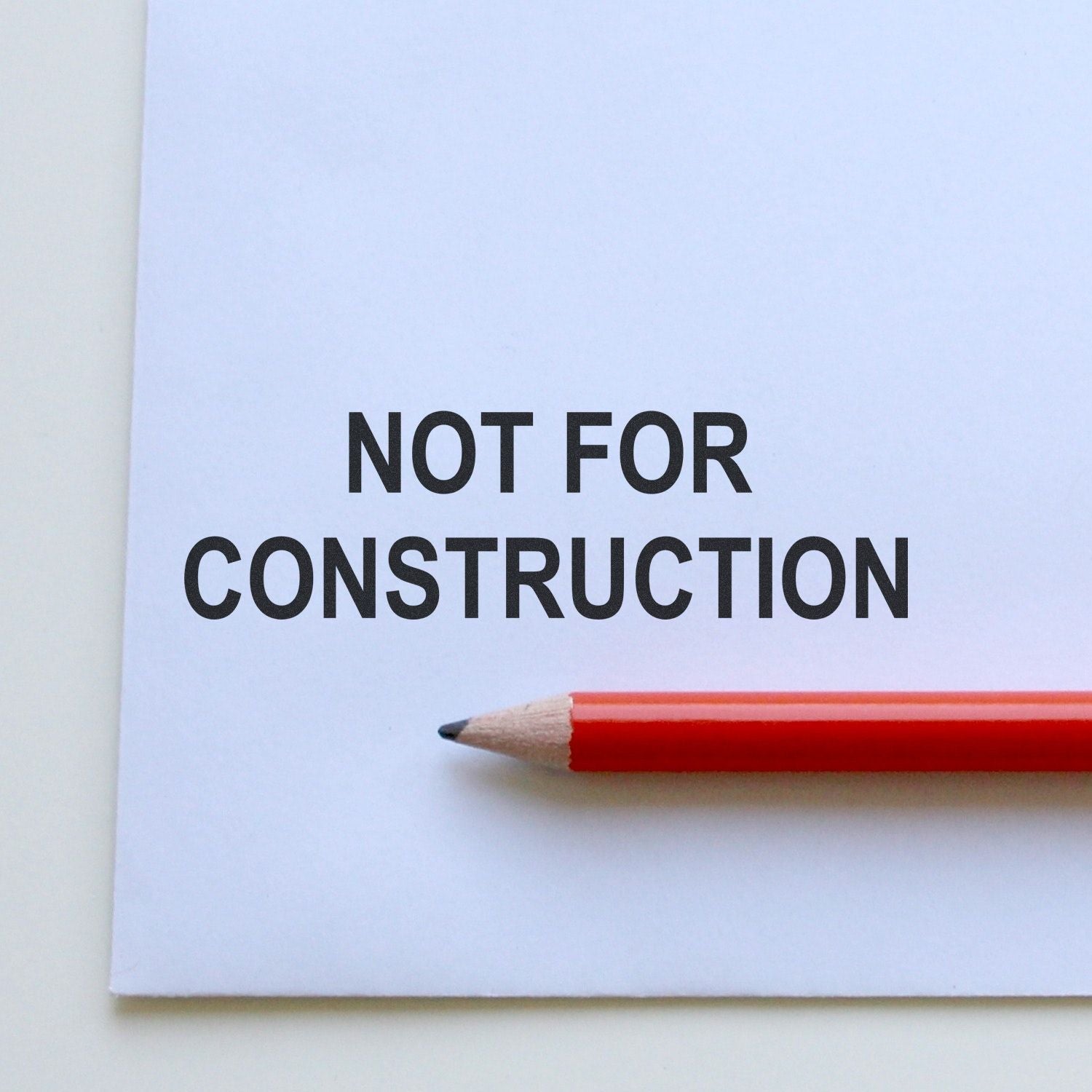 Not for construction text on white paper with red pencil, architectural drawing disclaimer sign.