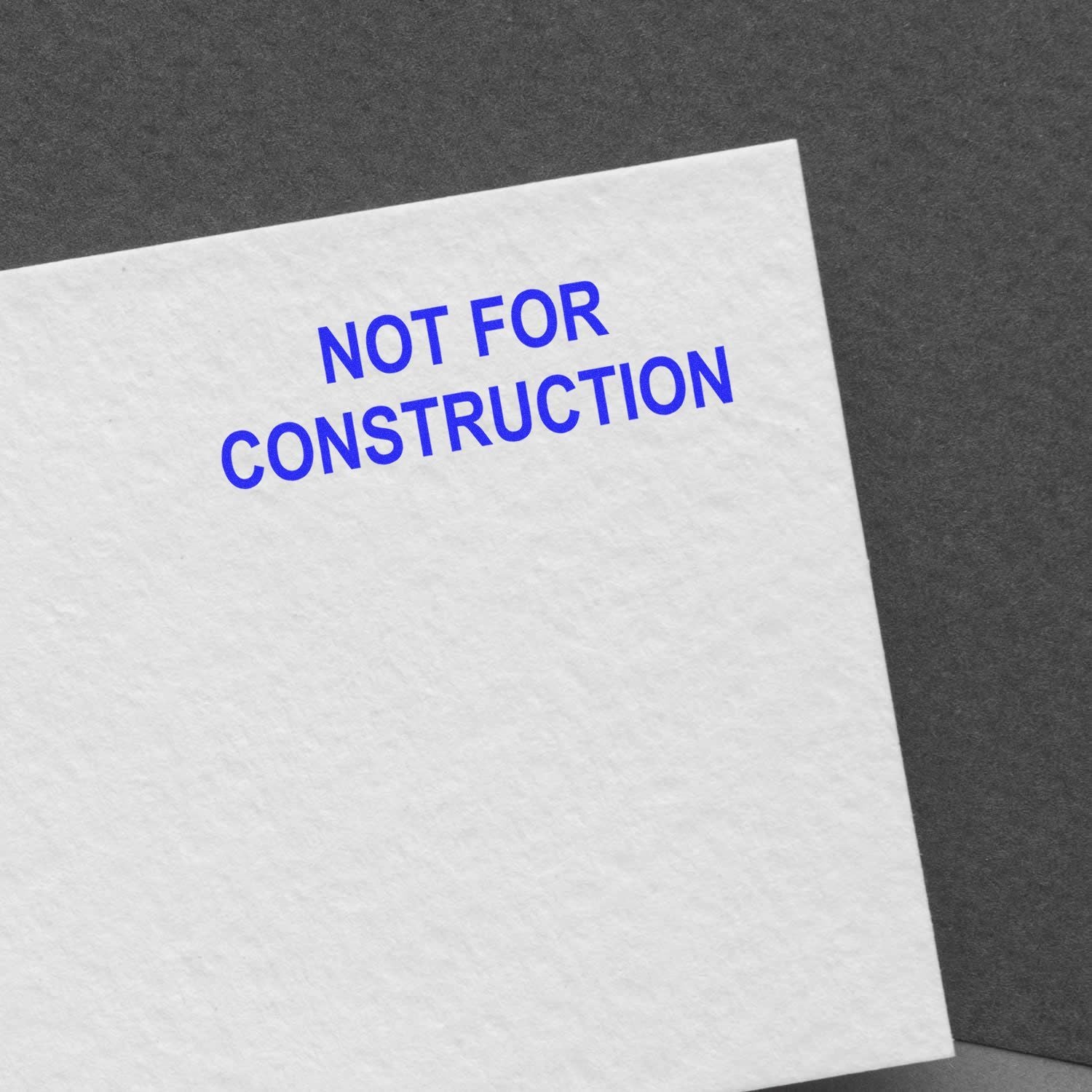 Close-up of white paper labeled Not for Construction on a gray background, architectural drawing disclaimer.