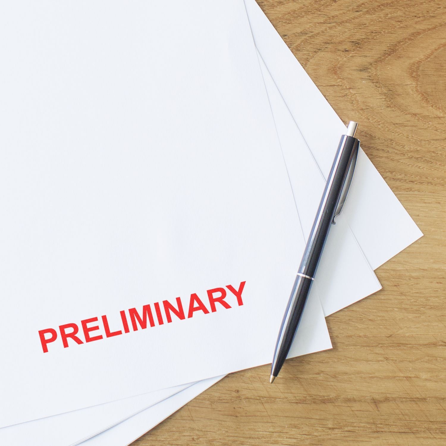 Preliminary document with pen on wooden desk, blank office papers for business planning and review.