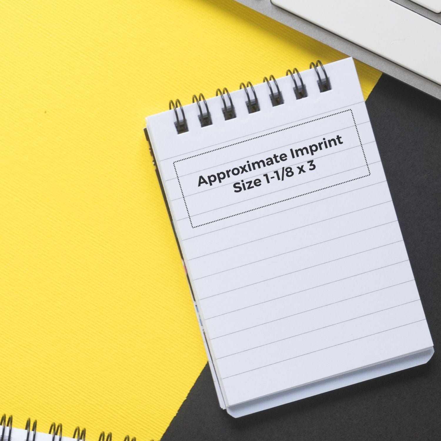 Spiral-bound notebook mockup on yellow and black background with Approximate Imprint Size 1-1/8 x 3 text label.