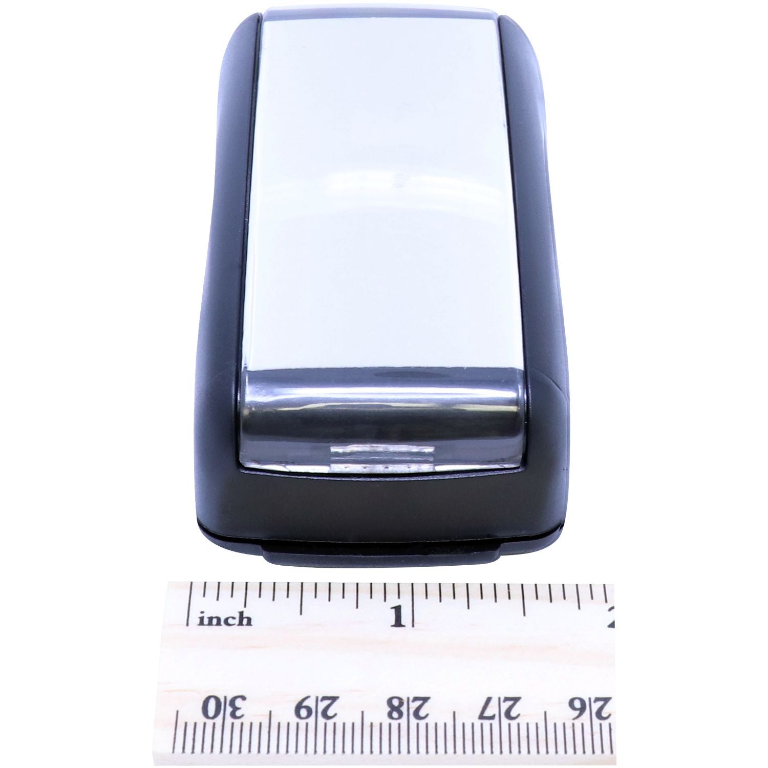 Close-up of compact black electronic device housing with chrome tip, shown next to inch ruler for size measurement.