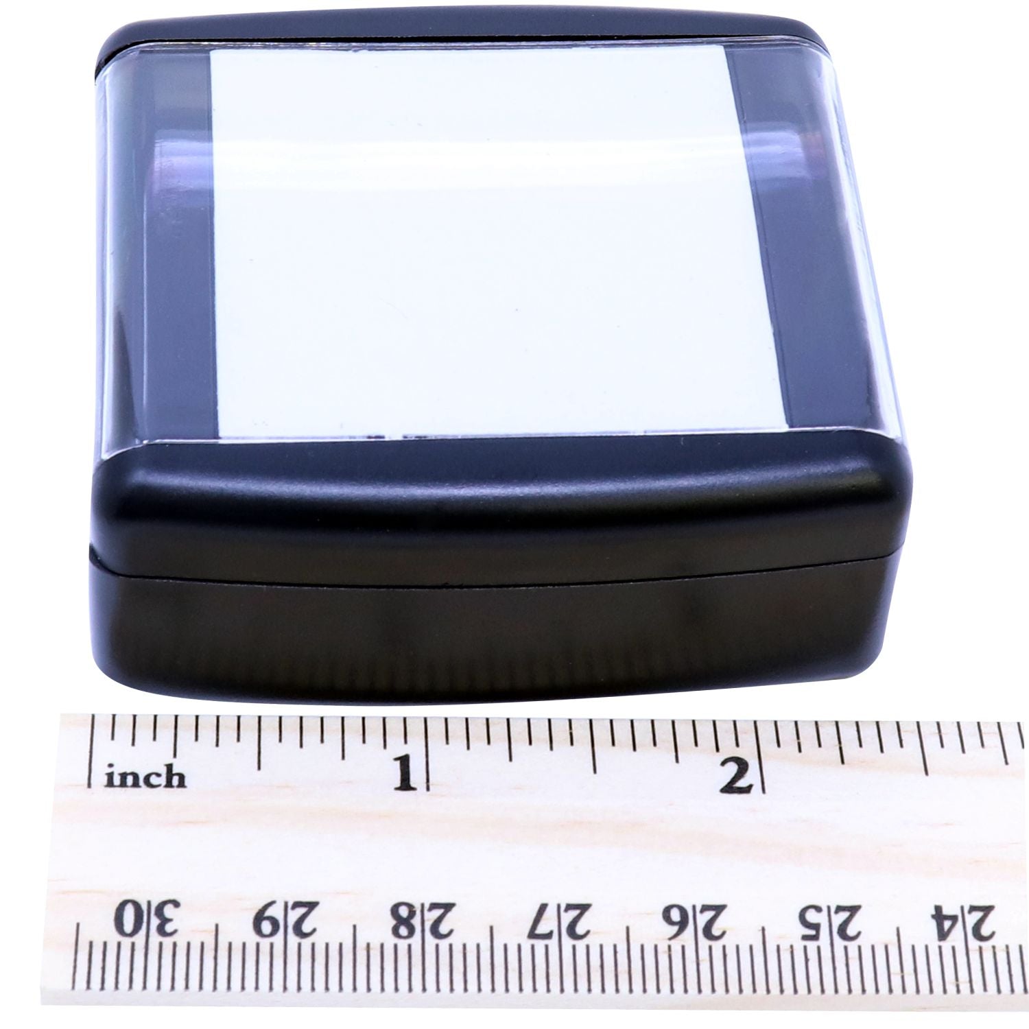 Close-up of compact blue-black plastic case with clear window, shown with inch ruler for size measurement.