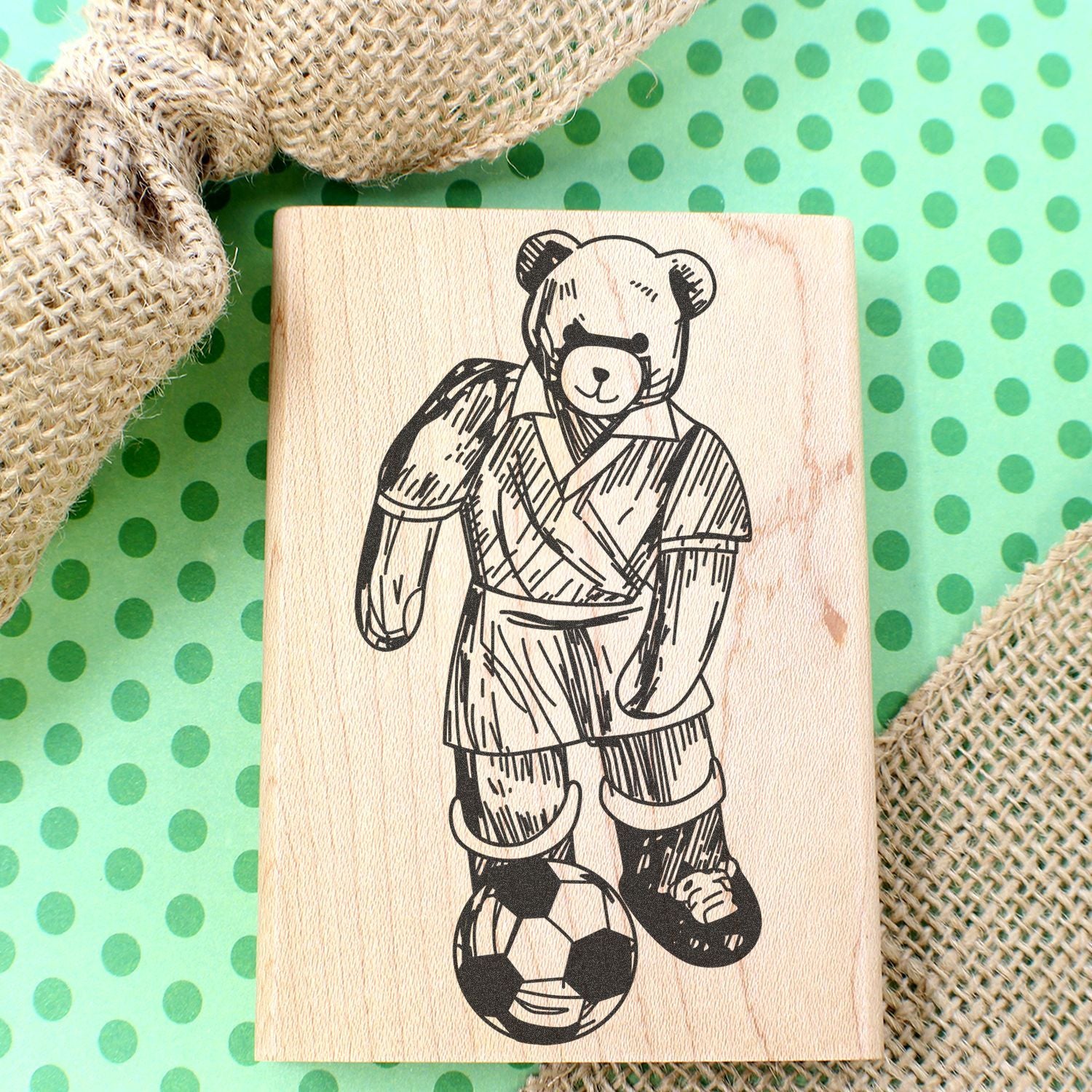 Wooden teddy bear soccer stamp on green polka dot background with burlap fabric decoration