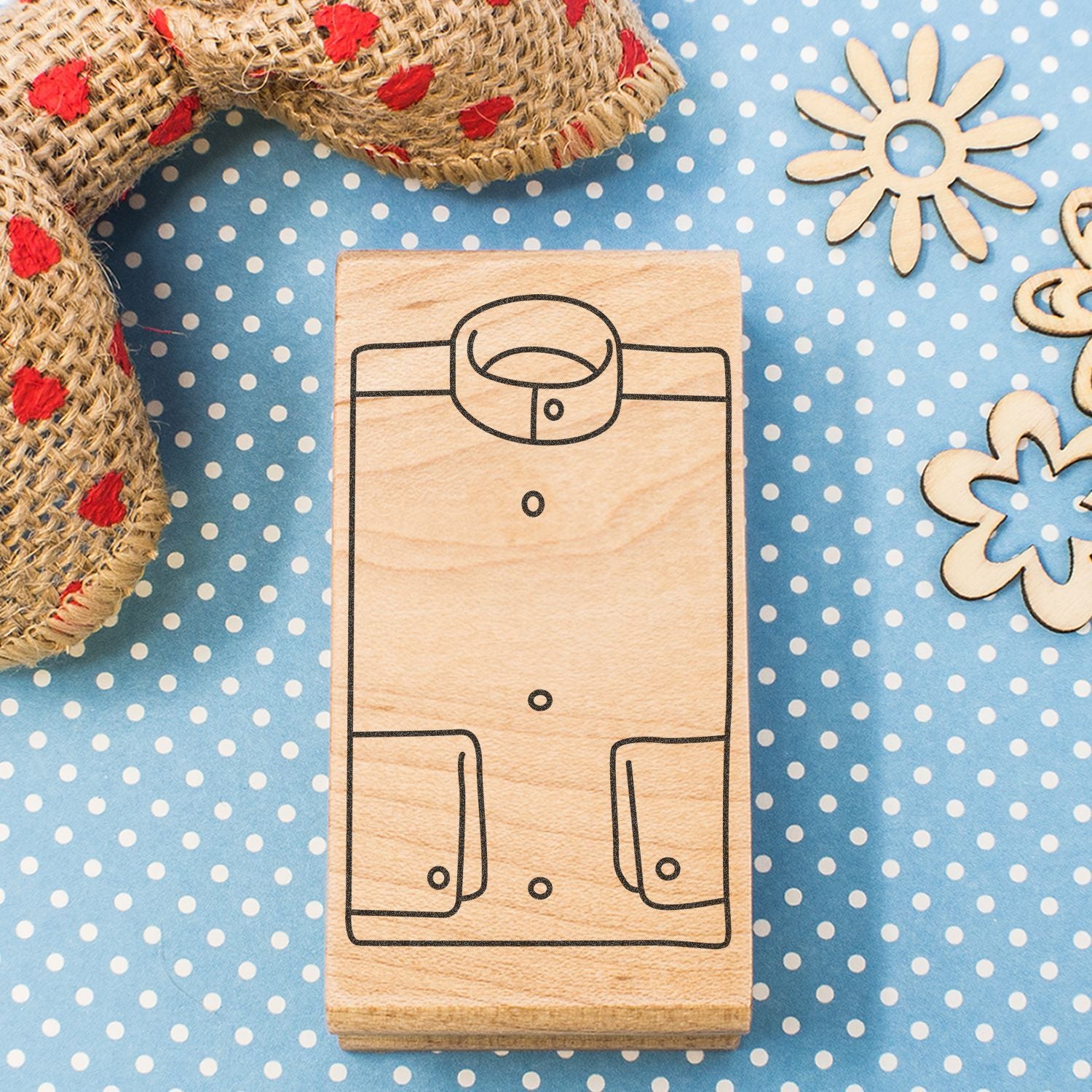 Wooden shirt stamp on blue polka dot background with rustic rope and floral decorations.