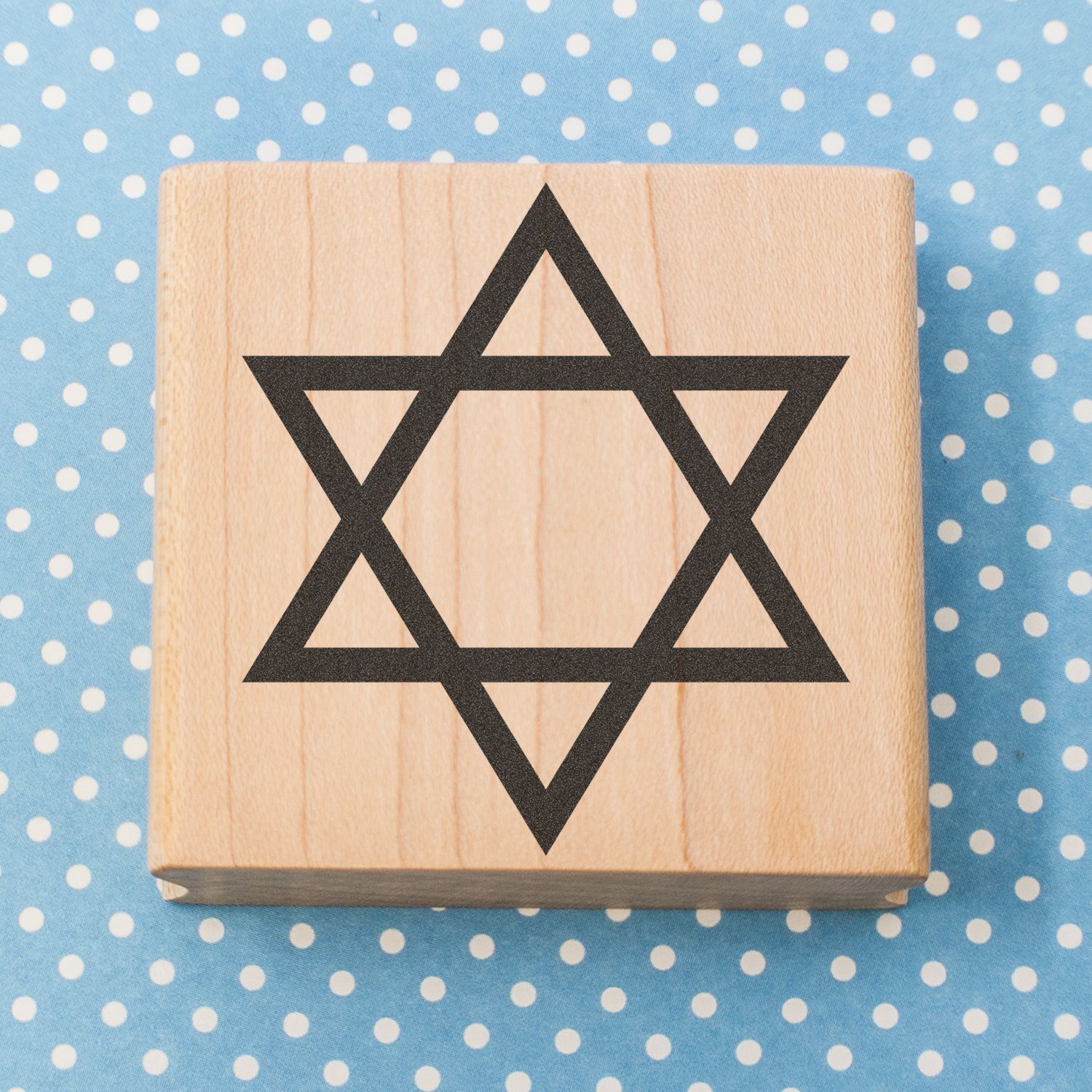 Wooden block with Star of David symbol on blue polka dot fabric background