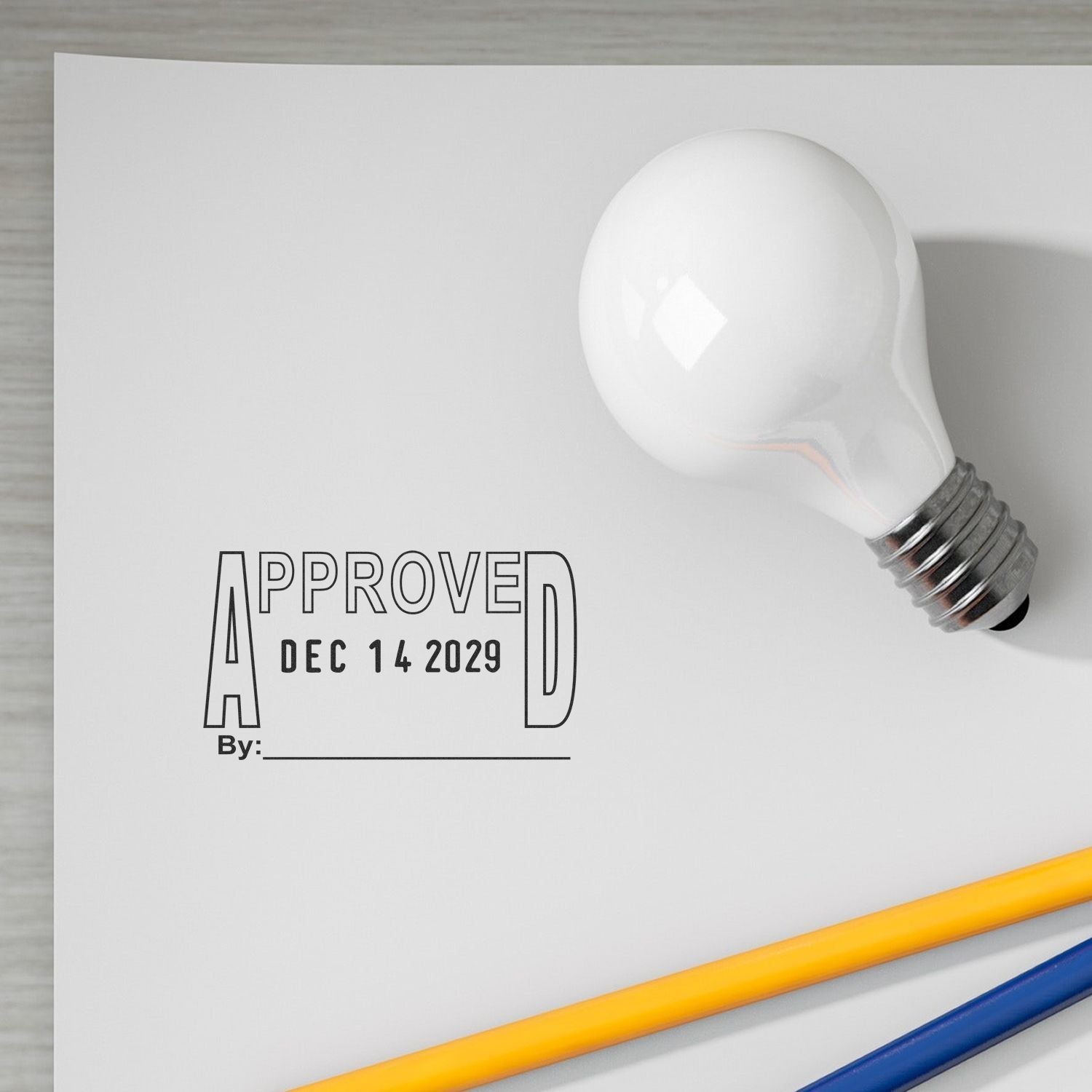White light bulb with approved date stamp on paper, office approval concept with pencils.