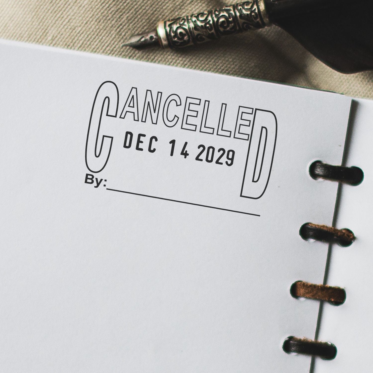 Close-up of a planner page stamped CANCELLED Dec 14 2029 with a fountain pen nearby.