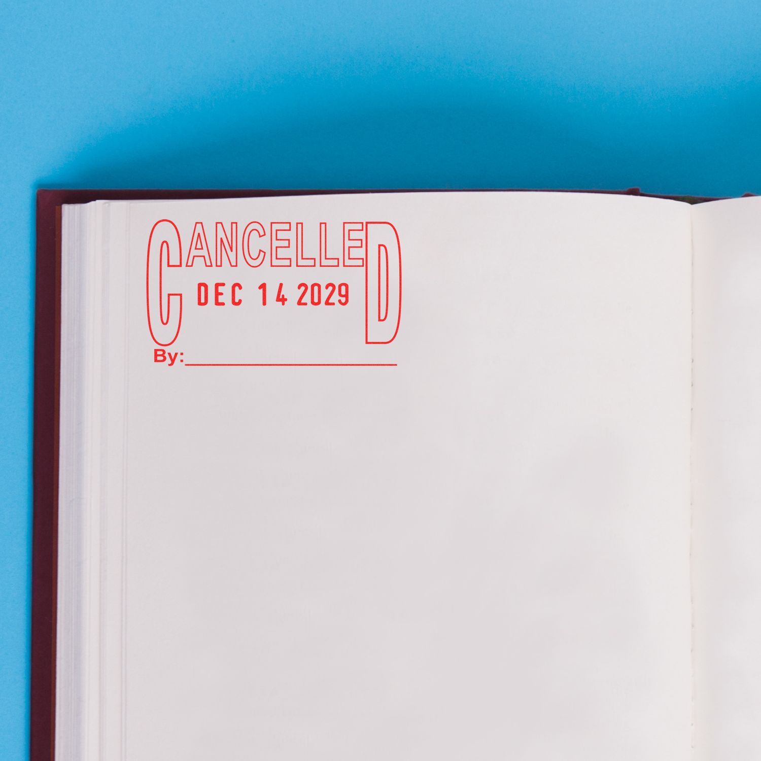 Open book page with red CANCELLED Dec 14 2029 stamp on blank paper background