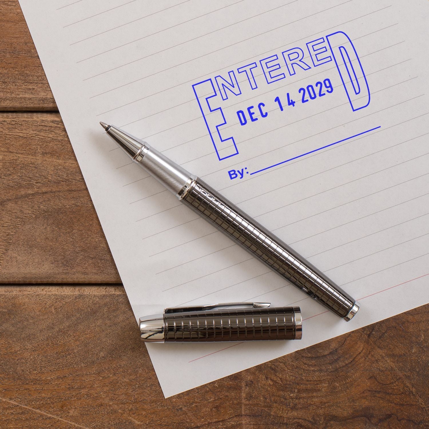 Close-up of a pen and notepad stamped Entered Dec 14 2029 on a wooden desk, illustrating future date entry or recordkeeping.
