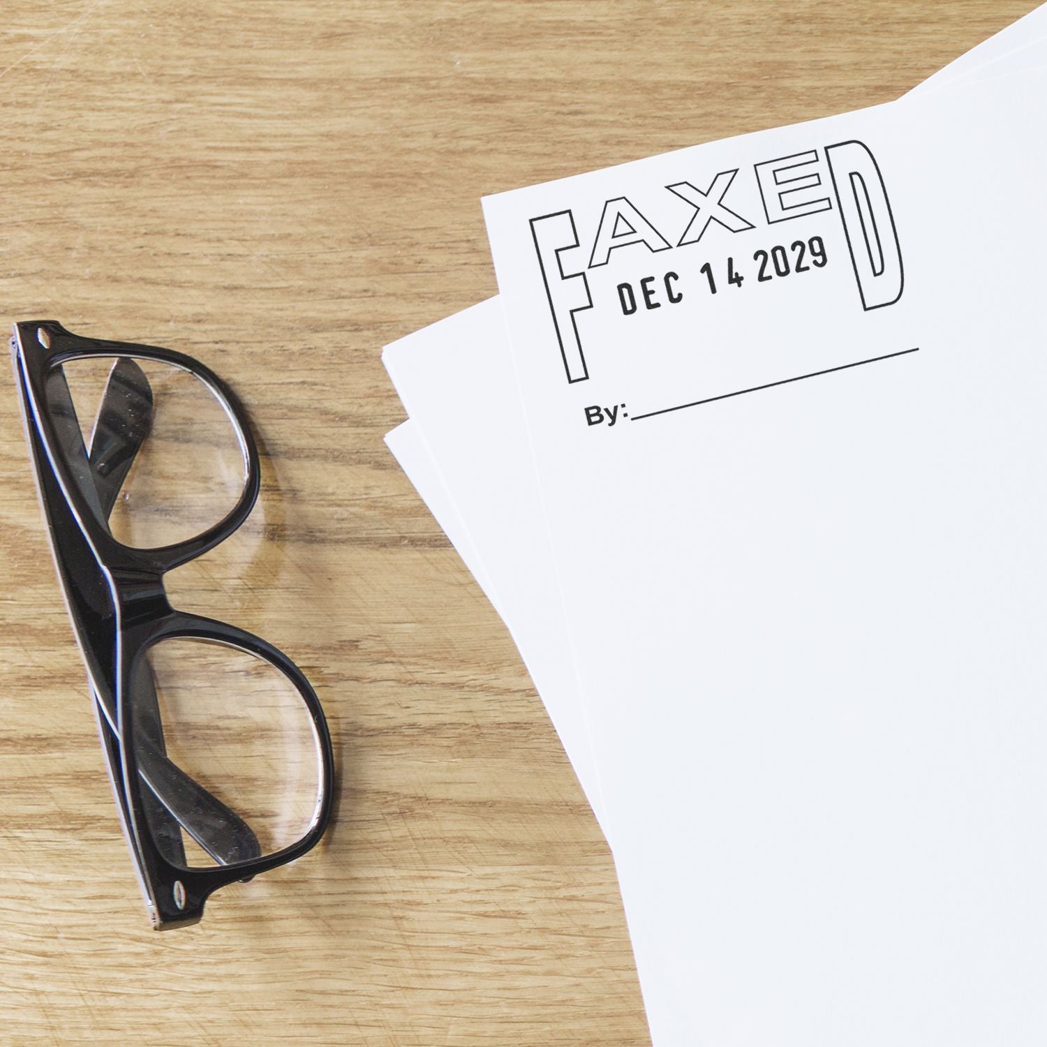 Black eyeglasses beside a faxed document on a wooden desk with FAXED Dec 14 2029 printed on top.