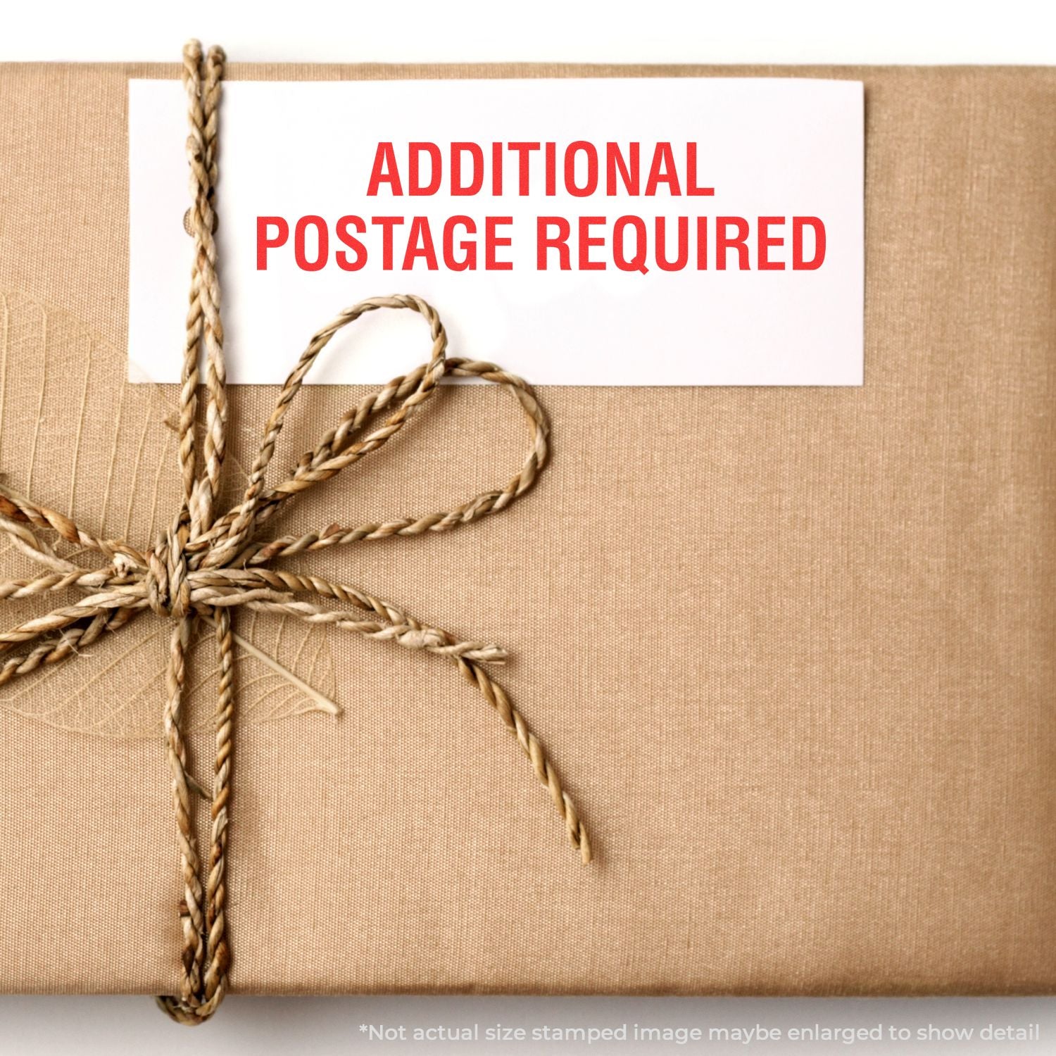 Package delivery label stamped Additional Postage Required on a tied parcel, indicating extra postage is needed for mailing