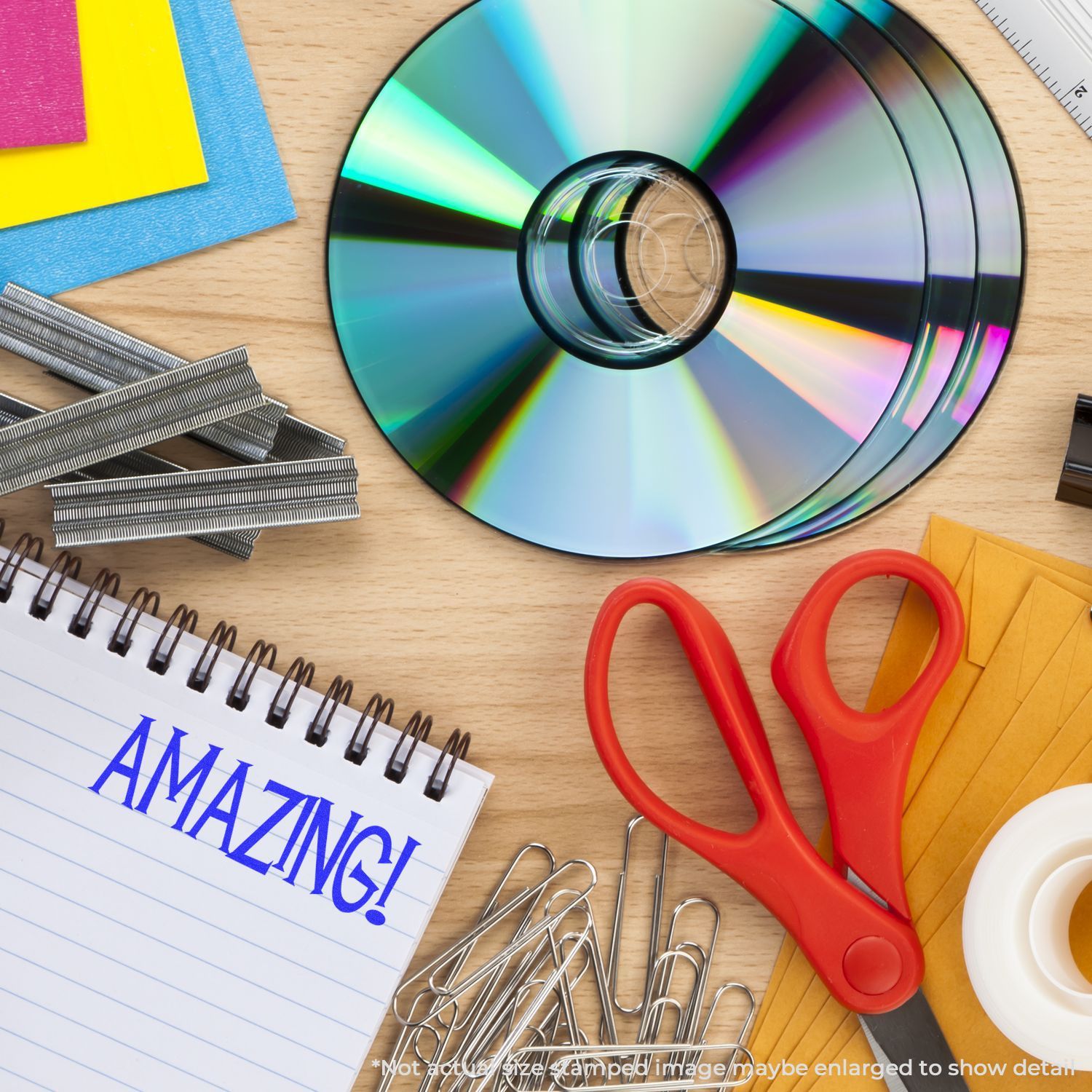 Magnifying glass over rainbow CD with stationery supplies and Amazing! notebook, symbolizing tech learning and research.