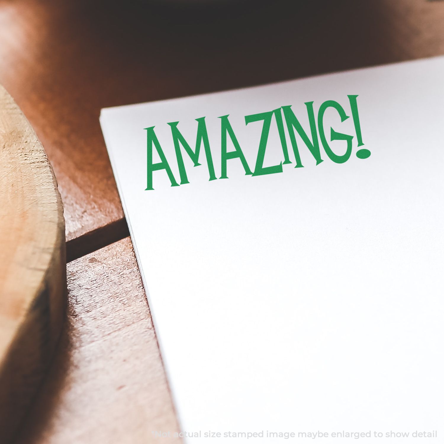 Close-up of a green AMAZING! typography card on a wooden surface, used for motivational message branding.