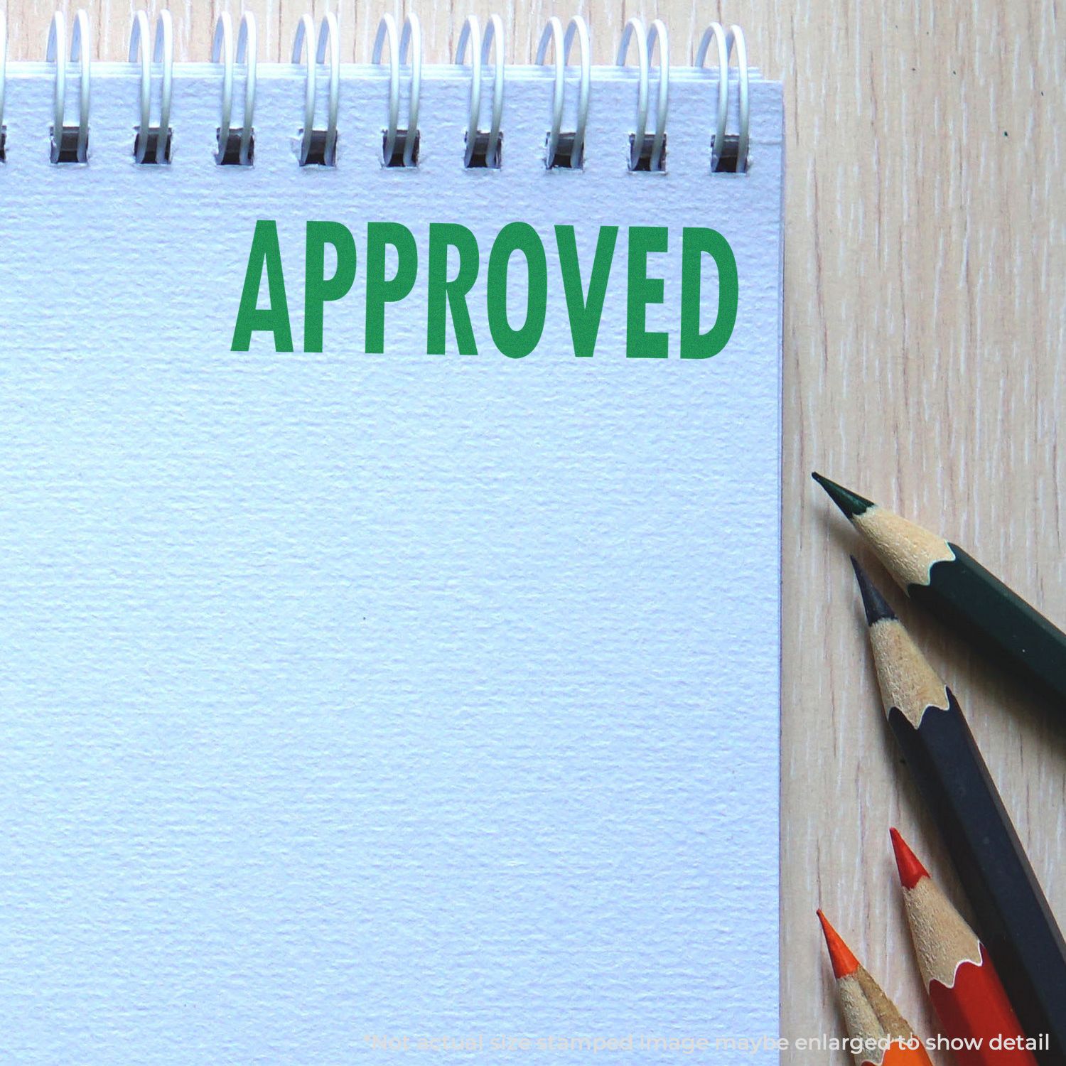 Approved stamp on a spiral notebook with colored pencils on a wooden desk, business approval concept.