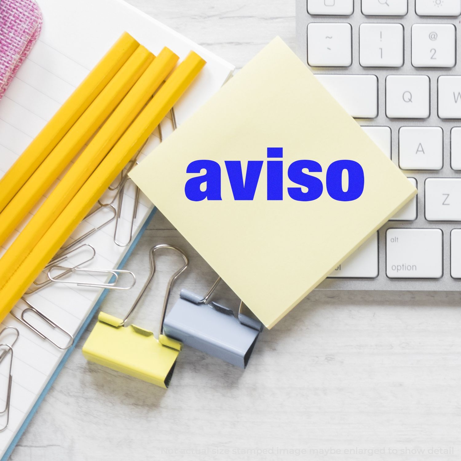Sticky note with aviso on a keyboard surrounded by office supplies and paper clips