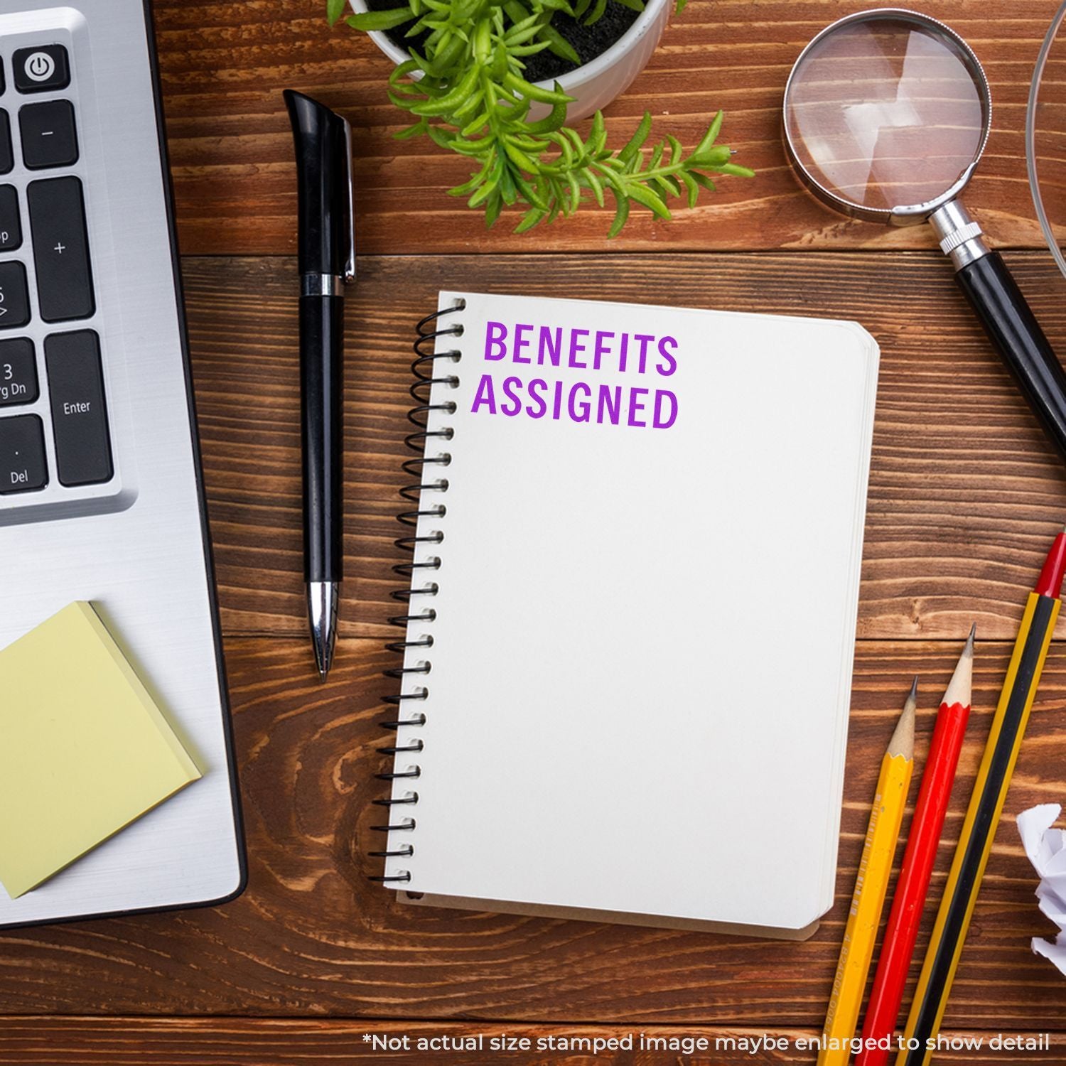 Benefits assigned concept: notebook reading 'BENEFITS ASSIGNED' on desk with pens and magnifying glass, employee benefits planning.