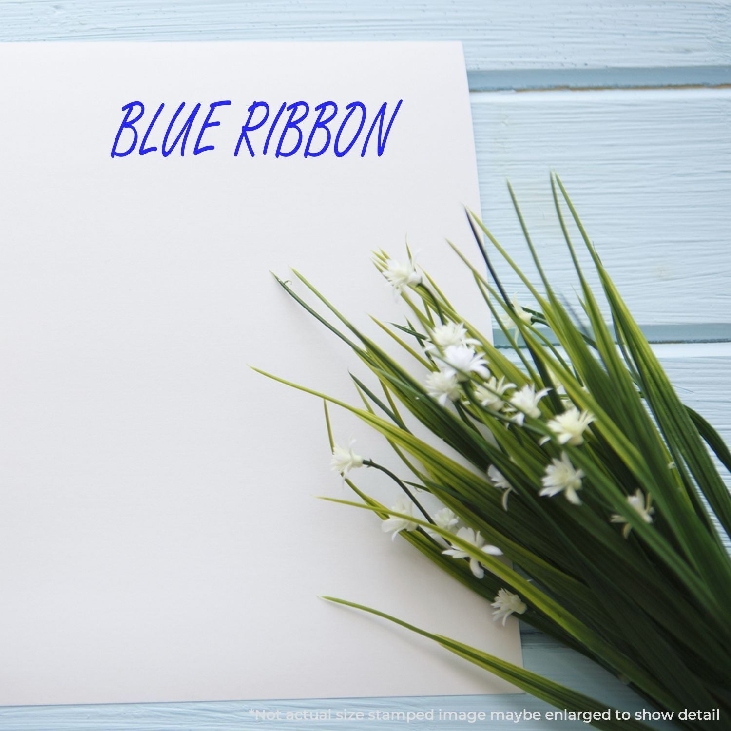 Blue ribbon stamp image on white paper with green artificial grass and small white flowers.