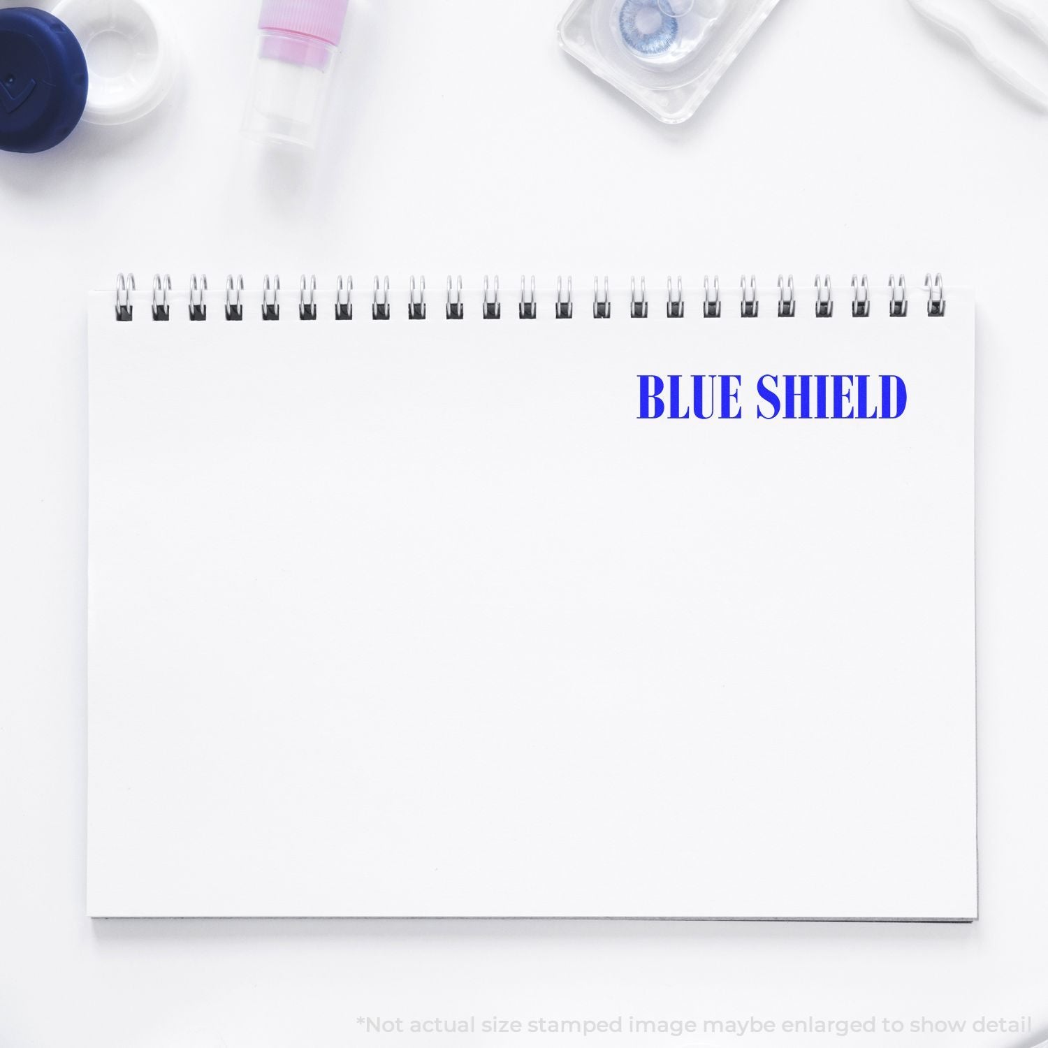 Blue Shield branded spiral notebook on clean desk with health supplies, ideal for office organization and training planning notes.
