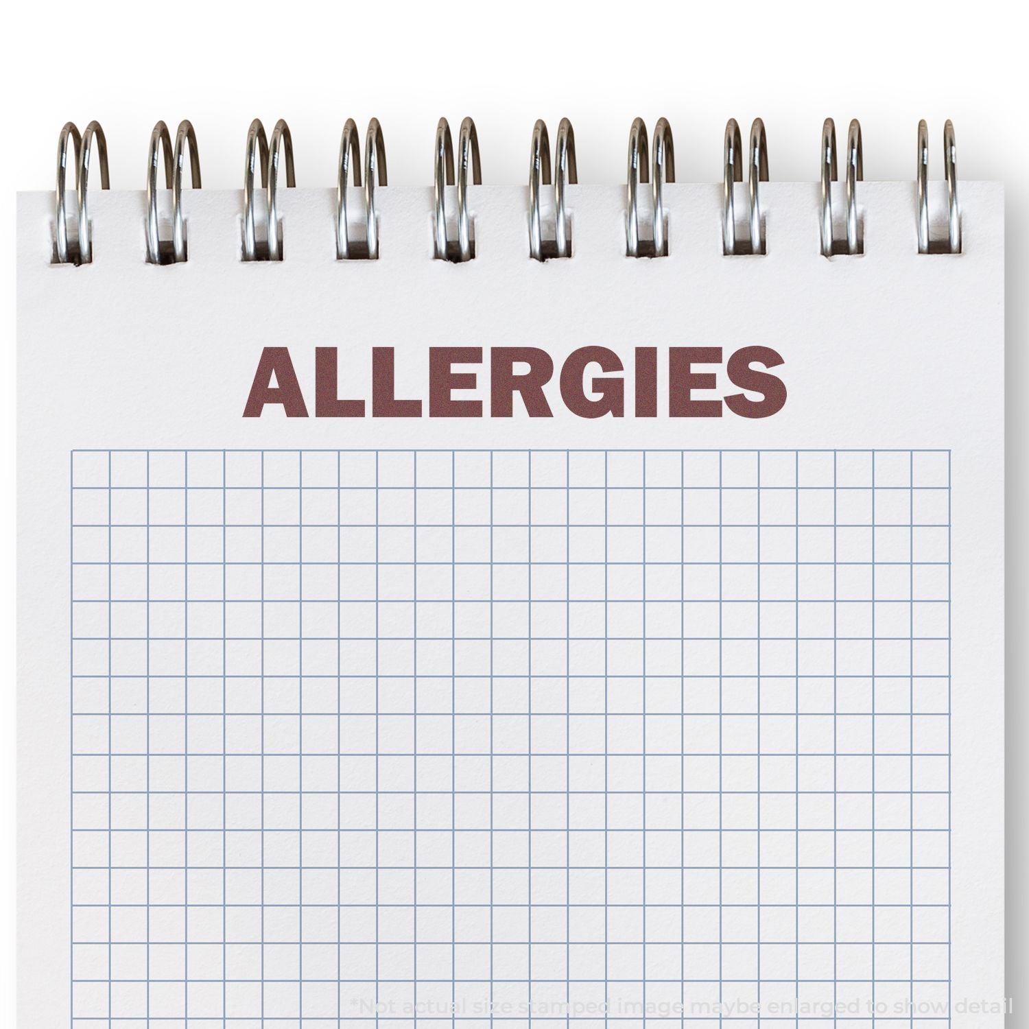 Spiral notebook with ALLERGIES title on a blank grid page, representing allergy tracking or health notes.