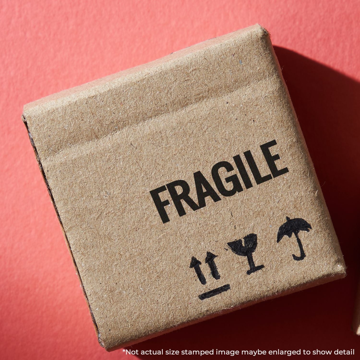 Close-up of FRAGILE shipping label on cardboard box with handle arrows, warning for careful handling and transport.