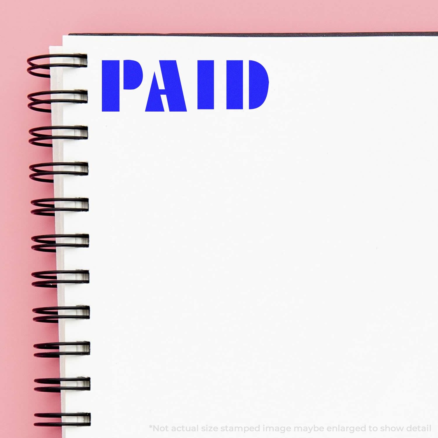 Blue PAID stamp on blank spiral notebook page with pink background