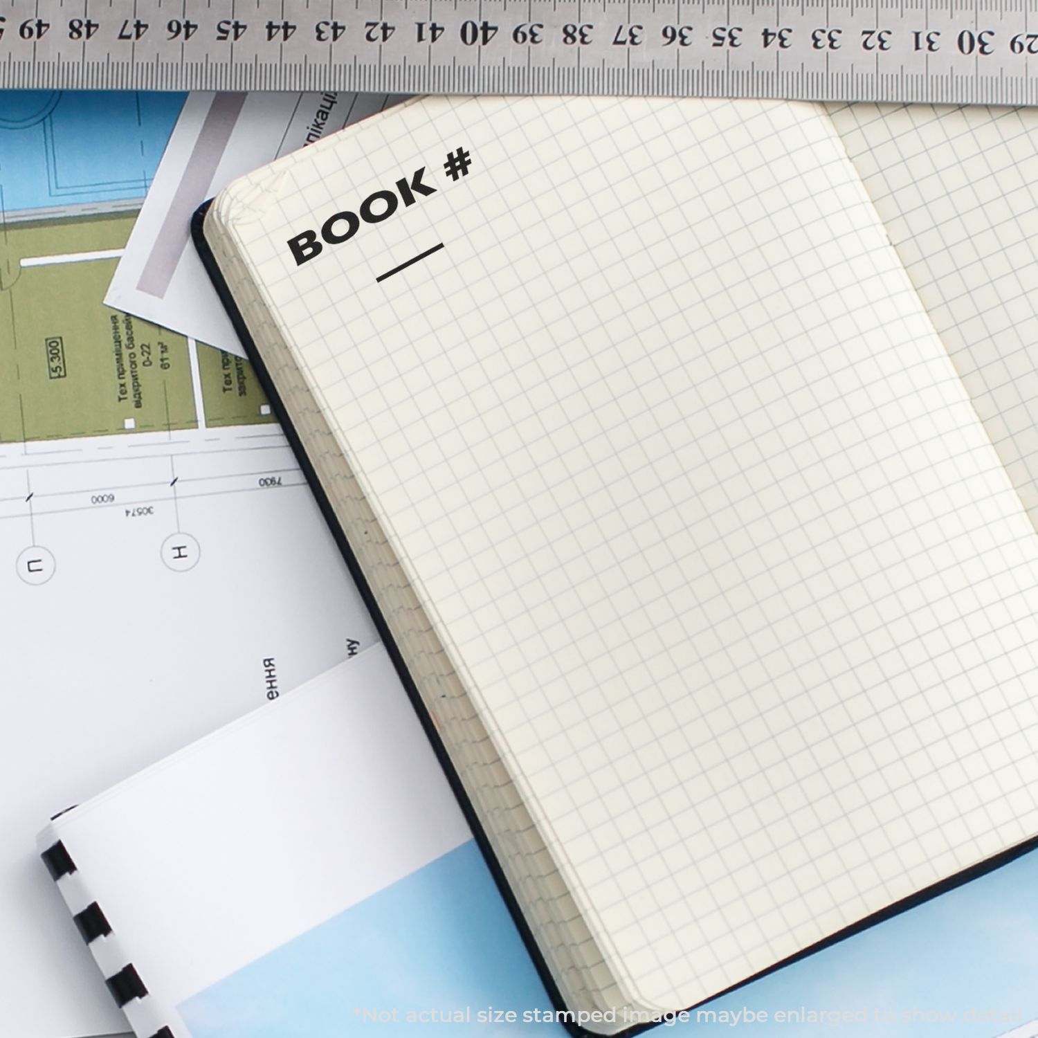Open notebook labeled BOOK with grid paper and ruler, symbolizing study planning and note-taking with school supplies for students.