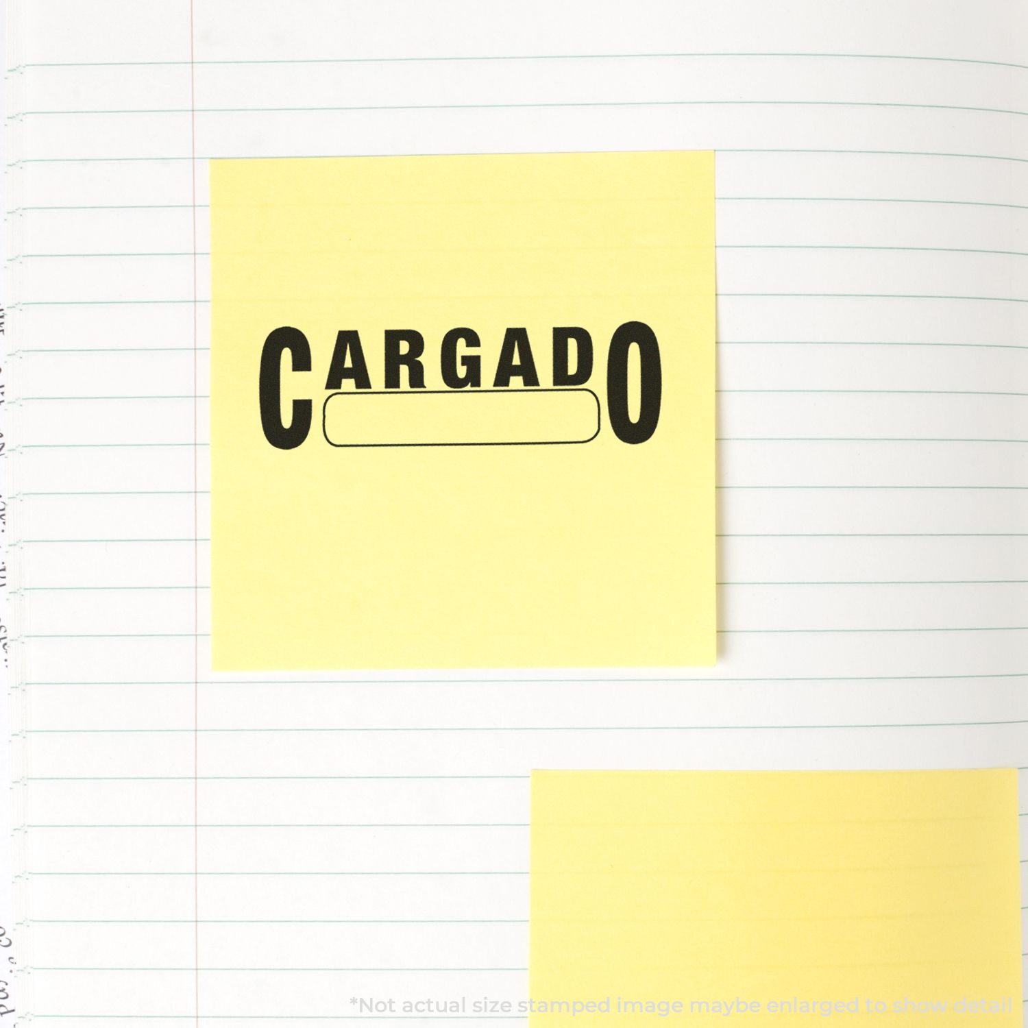 Yellow sticky note with CARGADO text and battery icon on lined notebook paper, office stationery background.