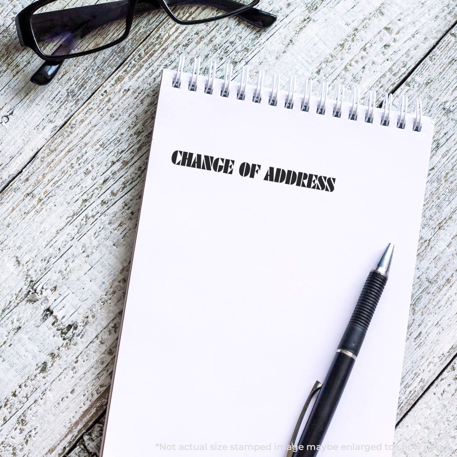 Change of Address checklist notebook with pen and eyeglasses on rustic wood, highlighting updating your mailing address for moving.