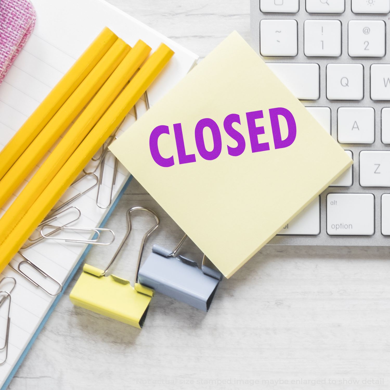 Closed office sign on sticky note with pencils and keyboard, suggesting school or workspace shutdown.
