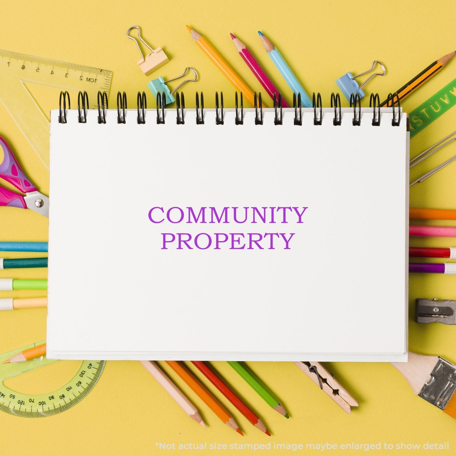 Community property notebook surrounded by colorful school supplies on a yellow background.