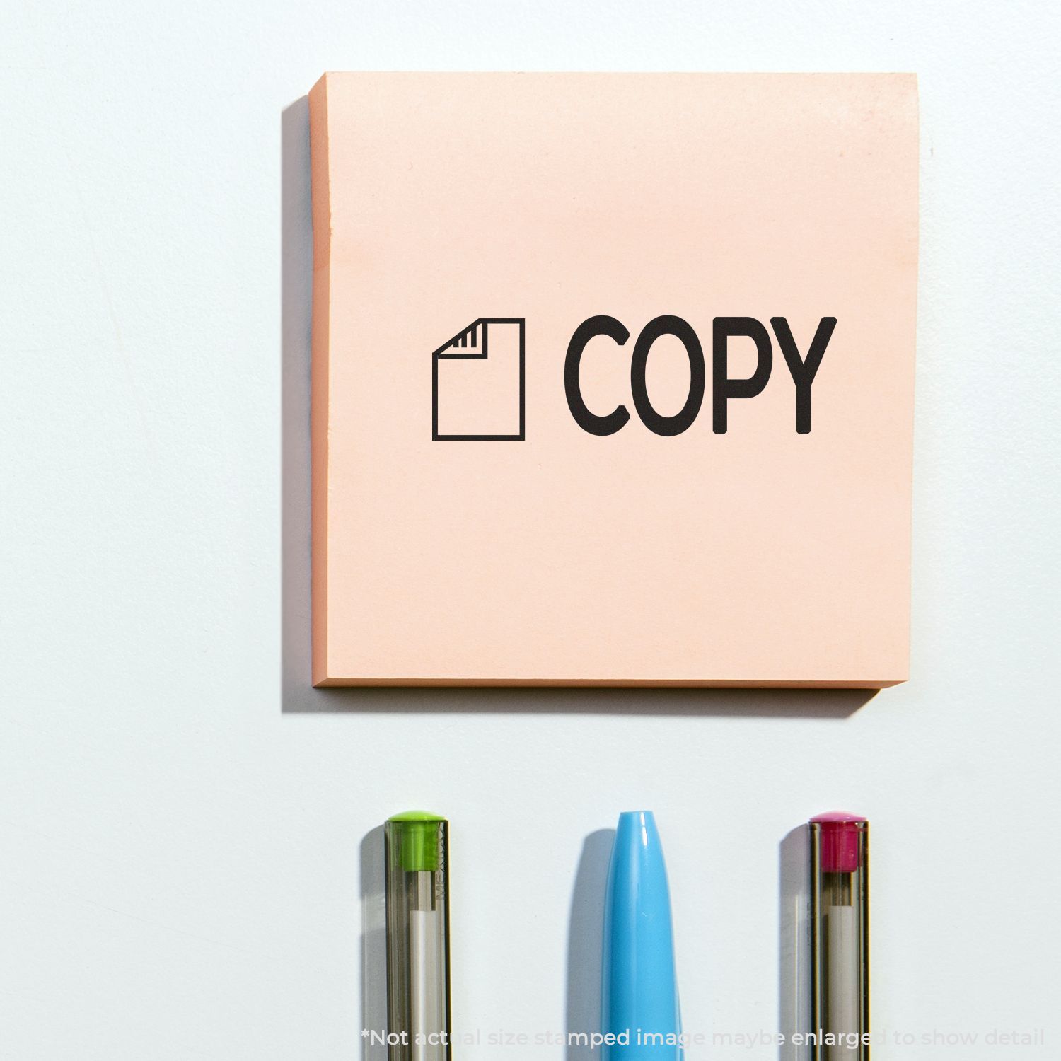 Pink sticky note with COPY logo and label icon above colorful markers, office message sign for copy and printing concepts