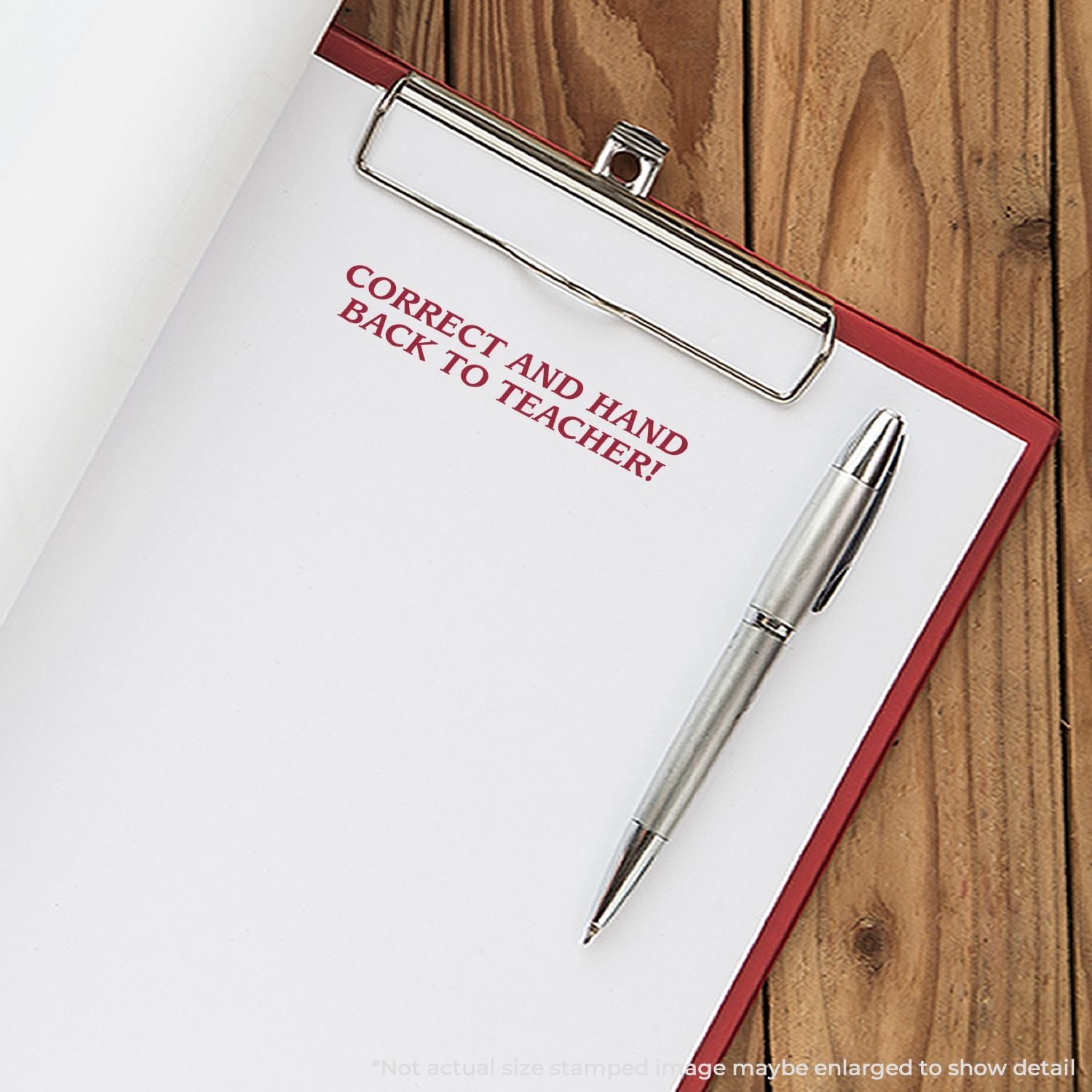 School notebook cover stamped Correct and hand back to teacher, with pen and metal clip on desk for grading return.
