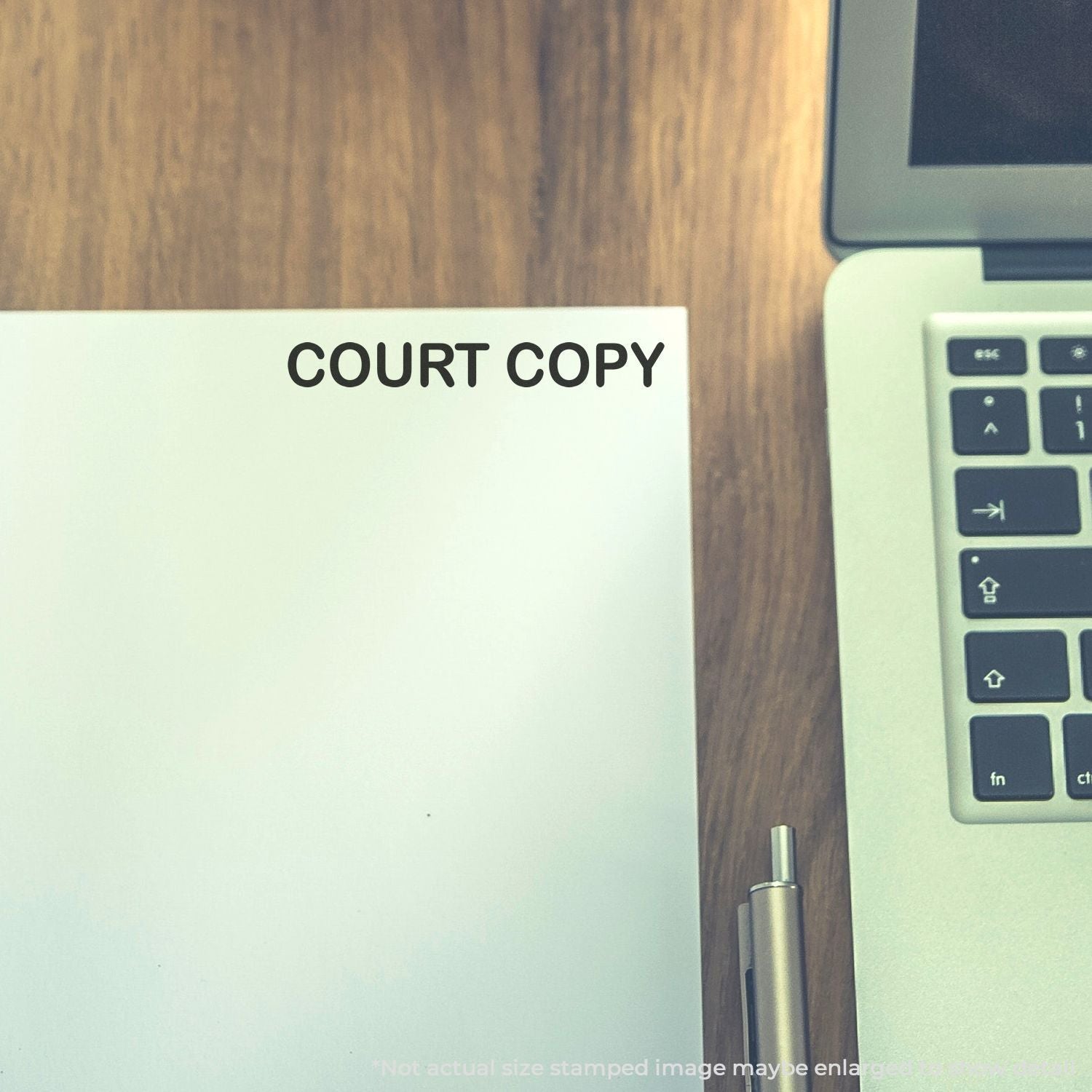 Court copy legal document on a wooden desk next to a laptop in an office setting.