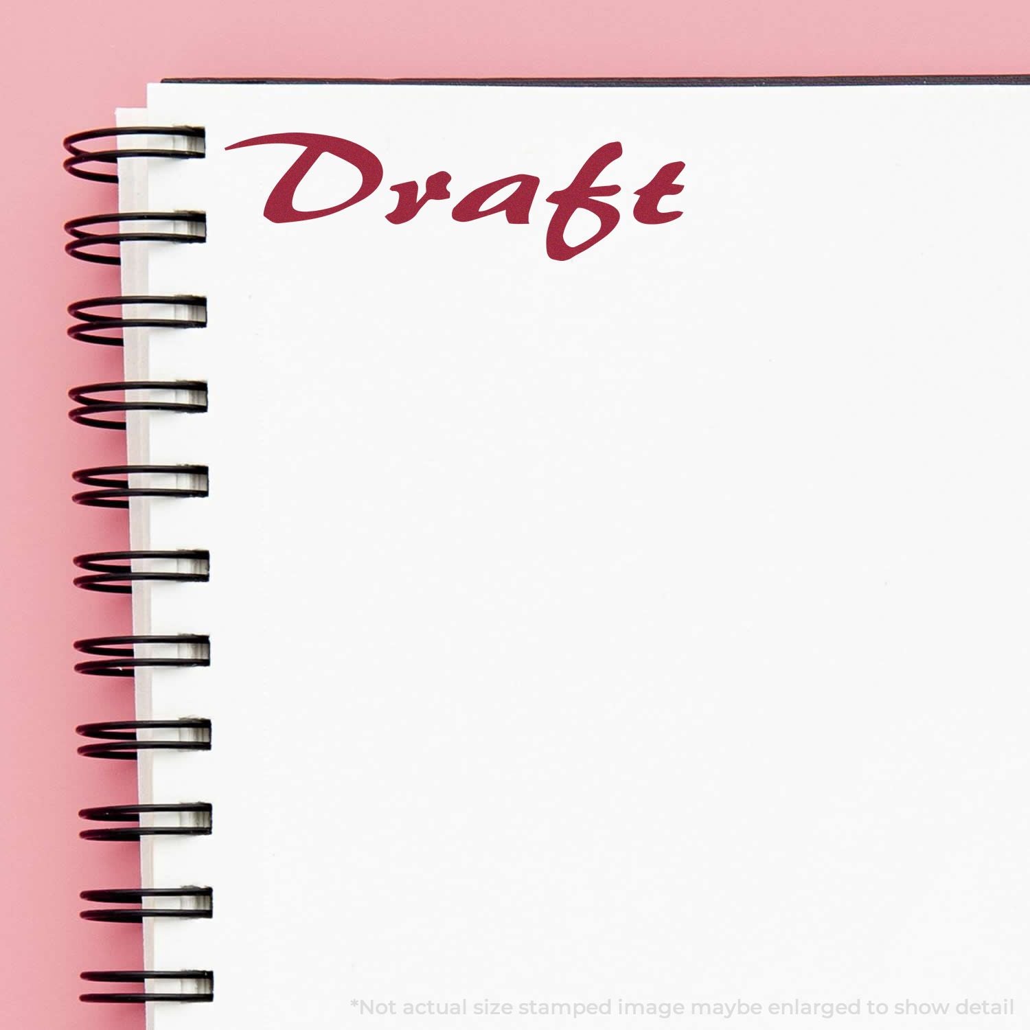 Spiral notebook with the word Draft on a white page against a pink background.