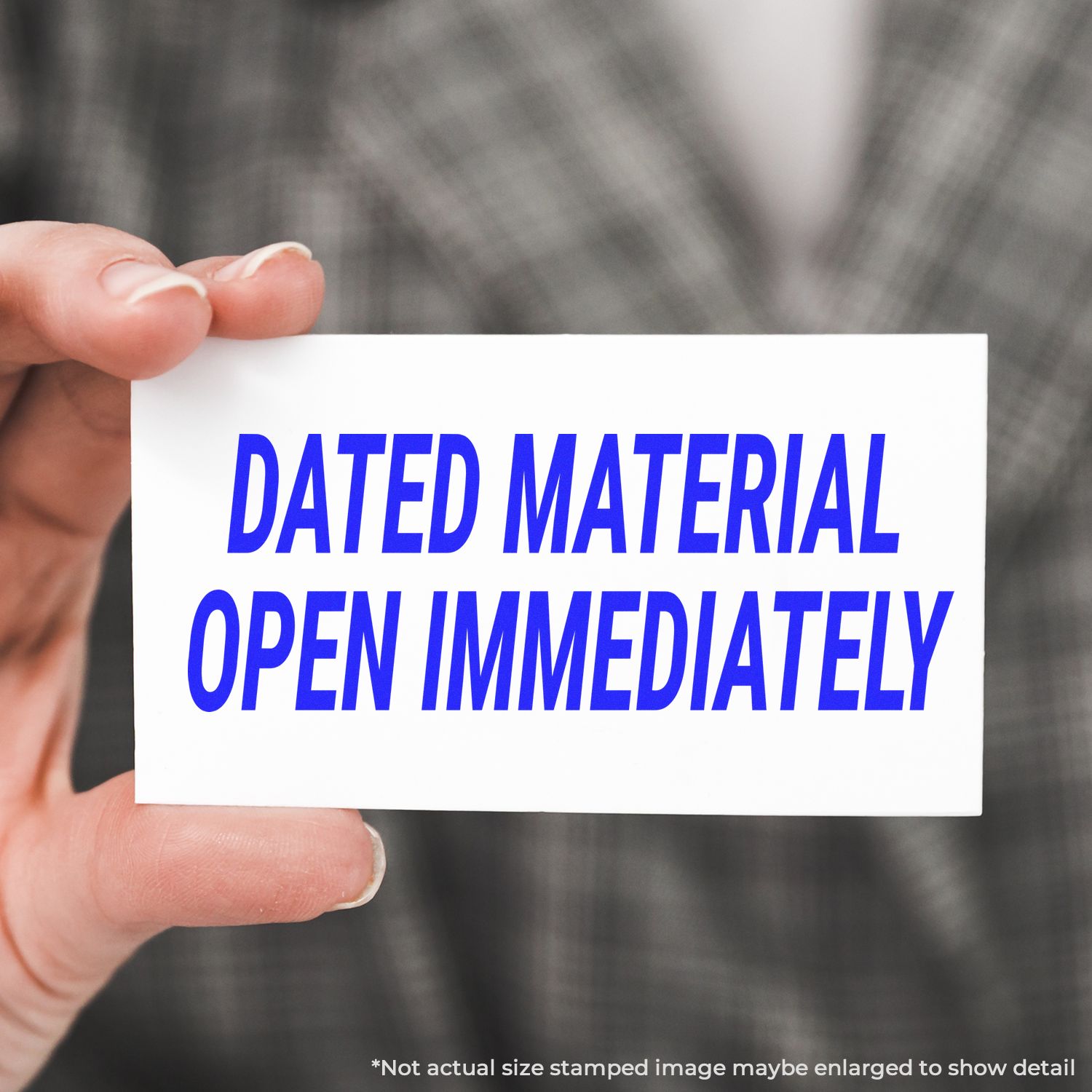 Hand holding a card that reads Dated Material Open Immediately on a blurred background.
