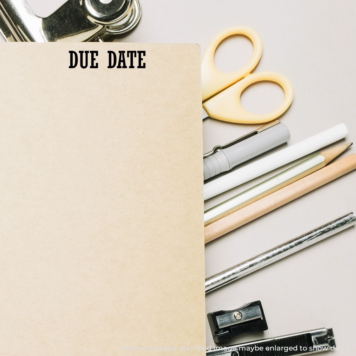 Due date clipboard with office stationery, scissors, pens, and pencil on a white background.