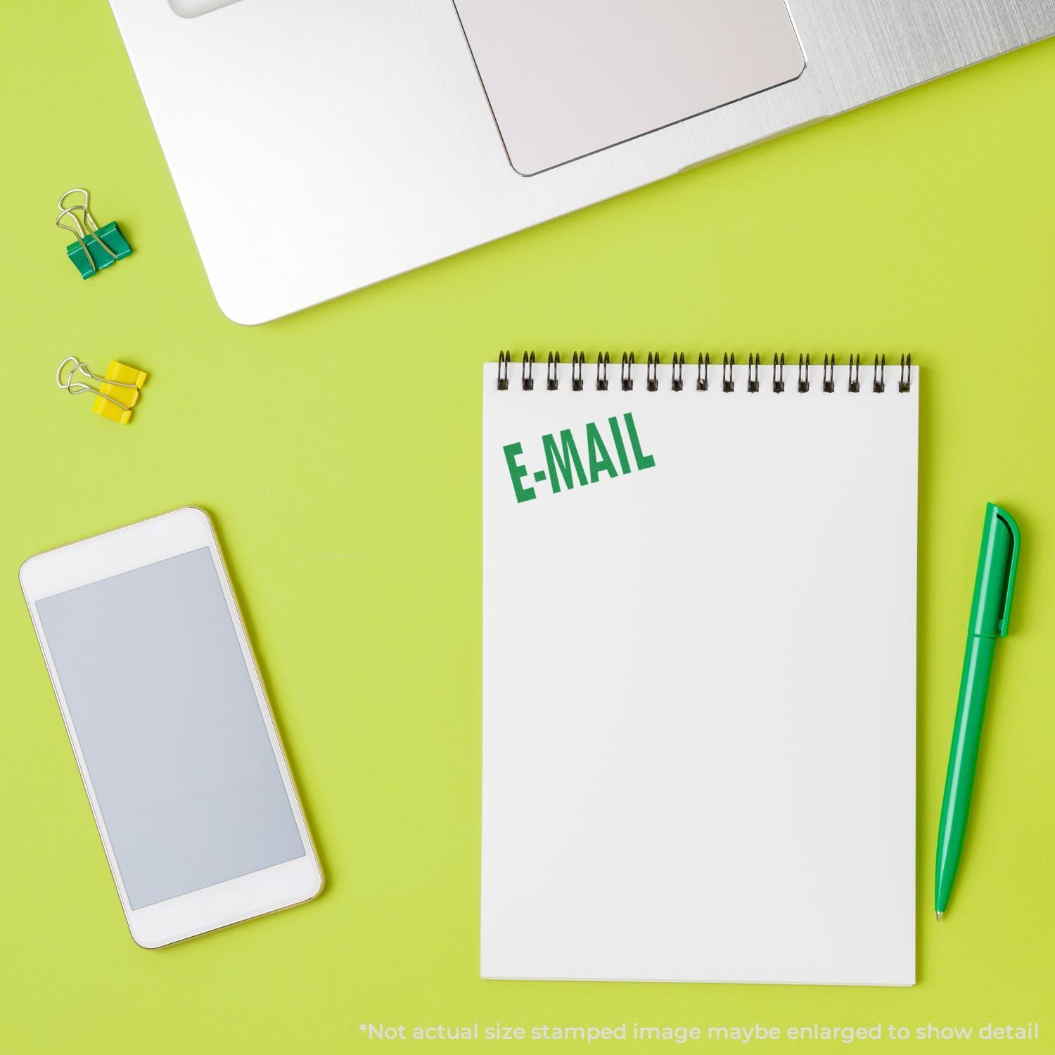 Green desk flat lay with laptop and phone above an E-MAIL notepad, suggesting email communication and marketing.