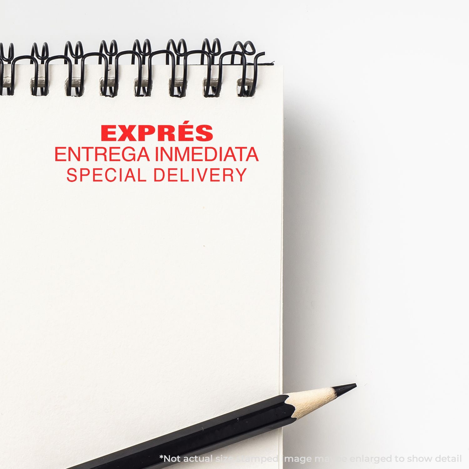 Spiral notebook with Expres Entrega Inmediata Special Delivery text and black pencil, minimal office stationery close-up.