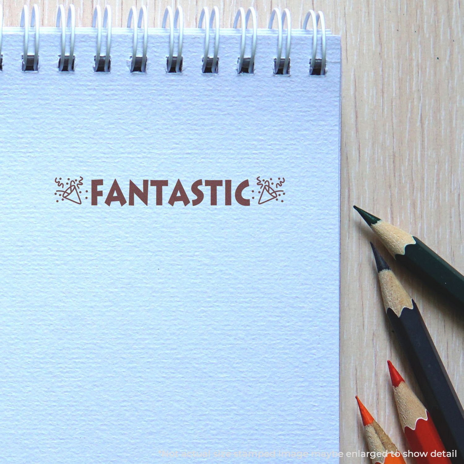 Blank spiral notebook with FANTASTIC text, colored pencils, and wooden desk background for creative stationery concept.