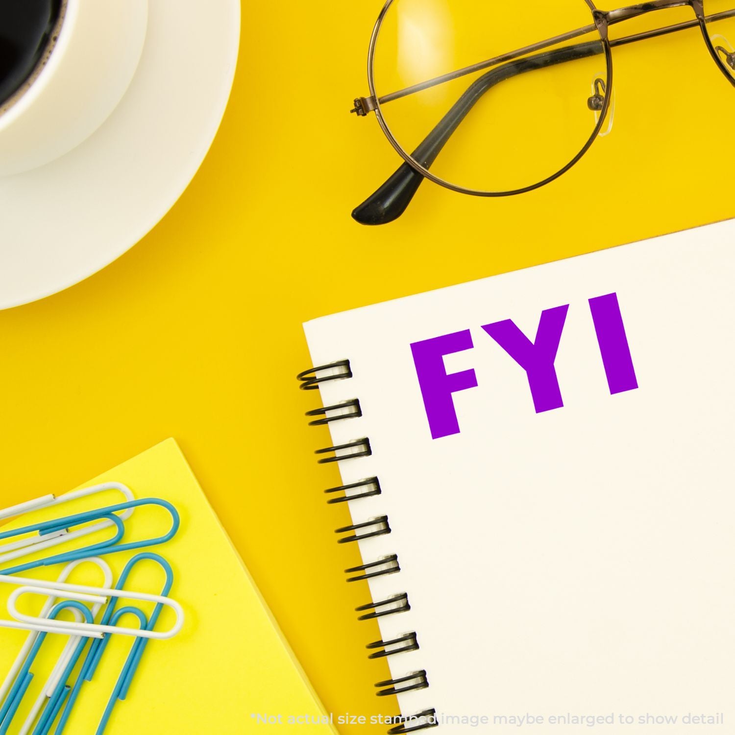 Office stationery on yellow desk: FYI notepad, stapler and paper clips for workplace reminders and tips.