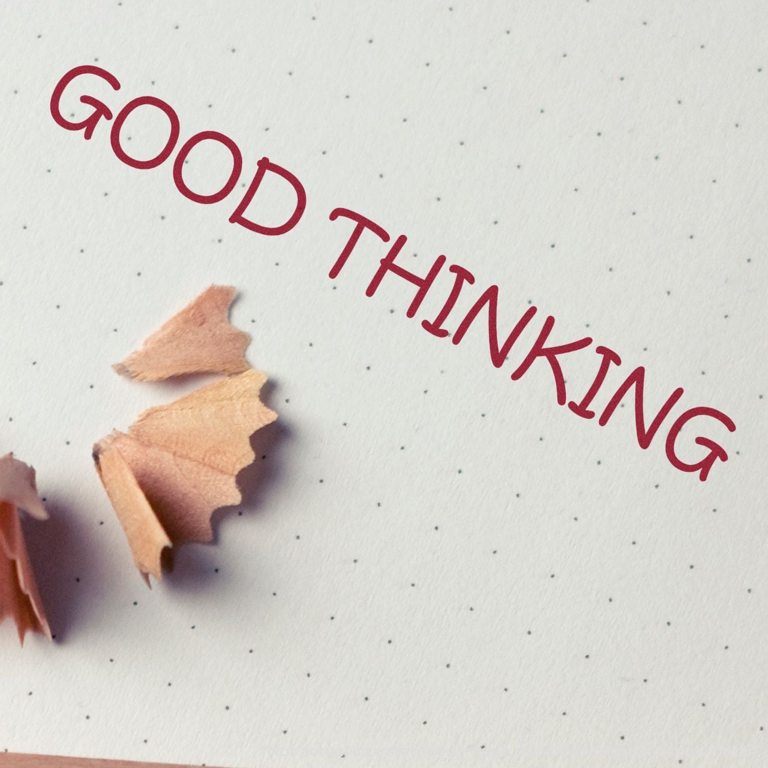Good Thinking motivational text on dotted notebook paper with pencil shavings, creative stationery background.