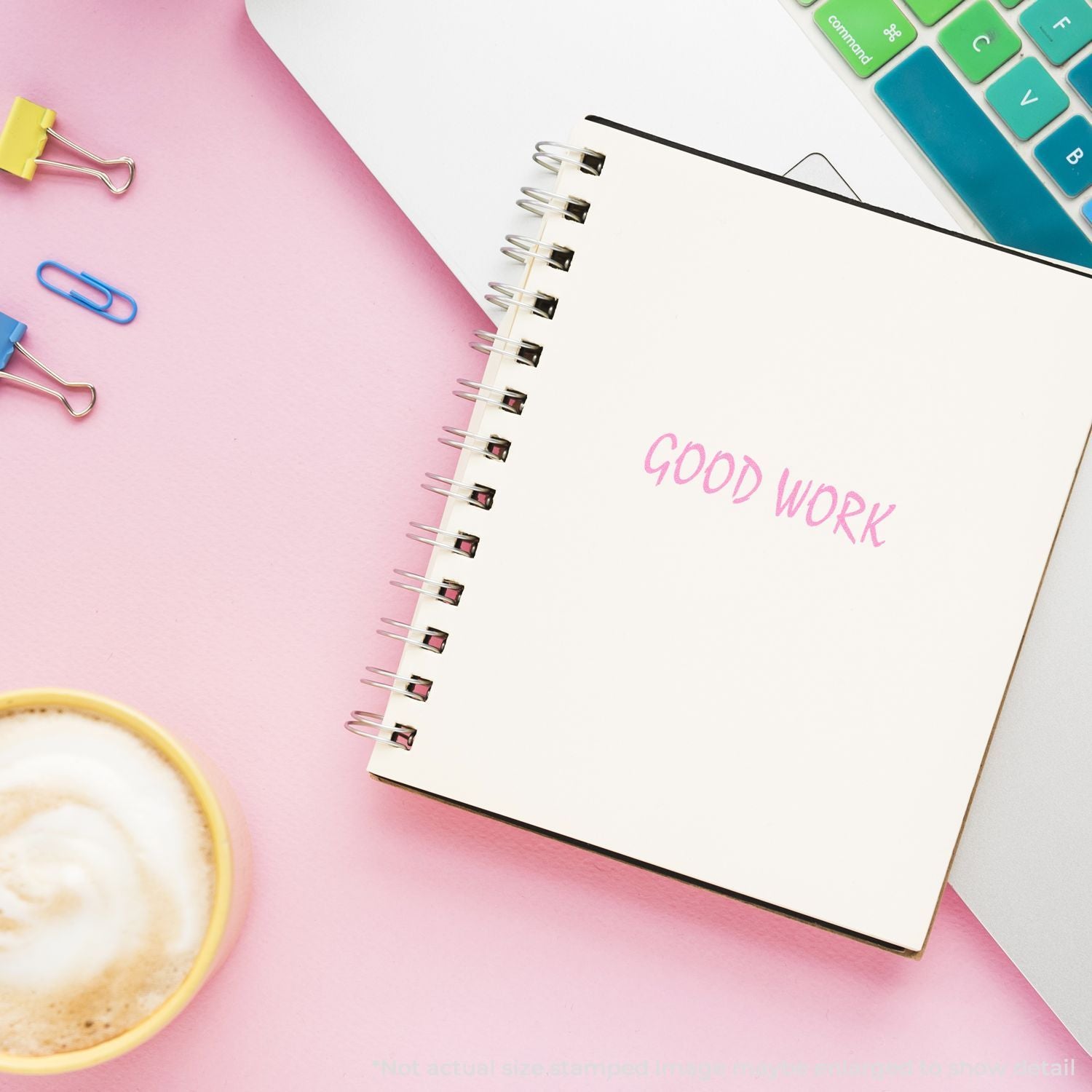 Pastel desk flat lay with spiral notebook reading Good Work, keyboard, coffee cup, and office supplies for creative workspace inspiration.