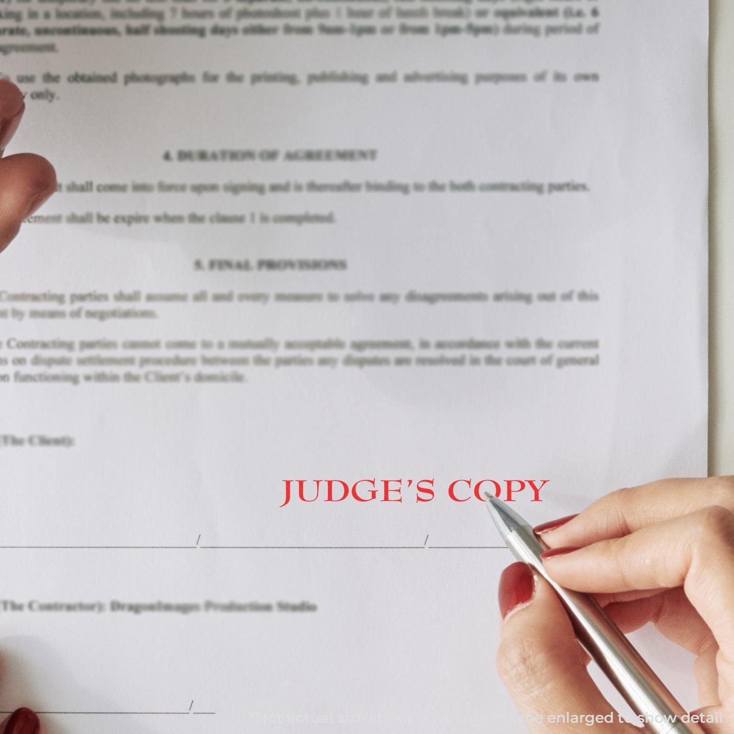 Close-up of hand holding a pen over a judges copy legal contract document, business agreement paperwork review.