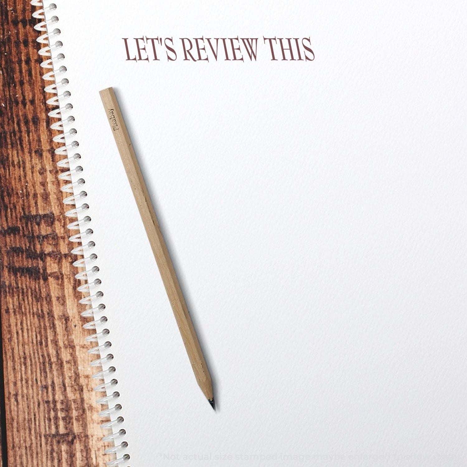 Spiral notebook with pencil and Lets Review This text on a wooden desk background.