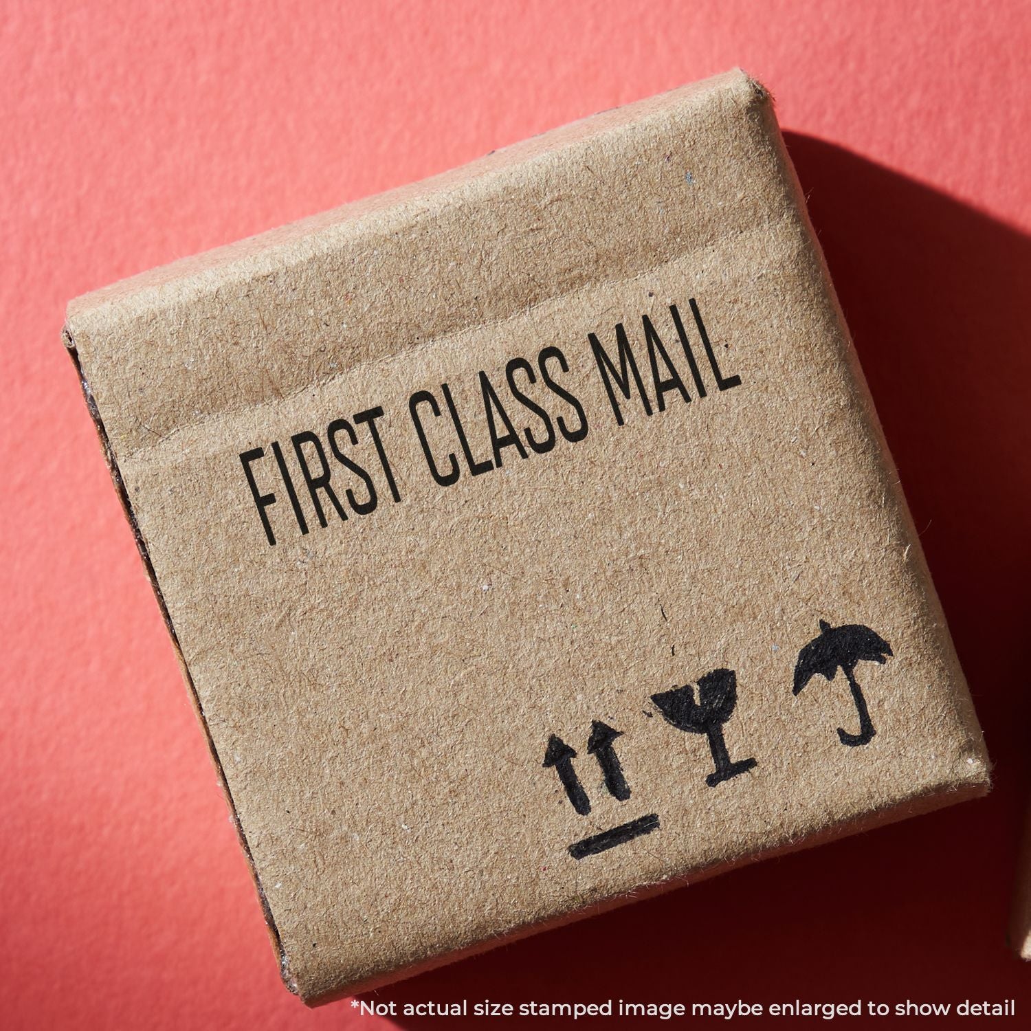 Small cardboard shipping box labeled First Class Mail with fragile handling icons on a red background.
