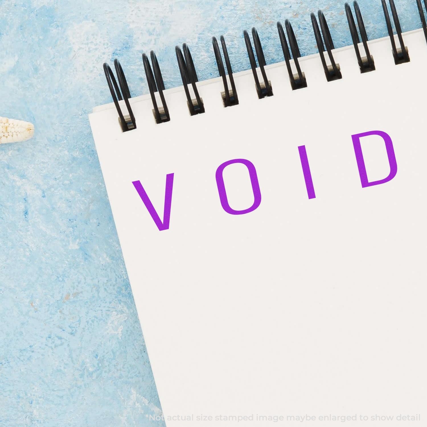 Spiral notebook with VOID text on white paper against a blue textured background.