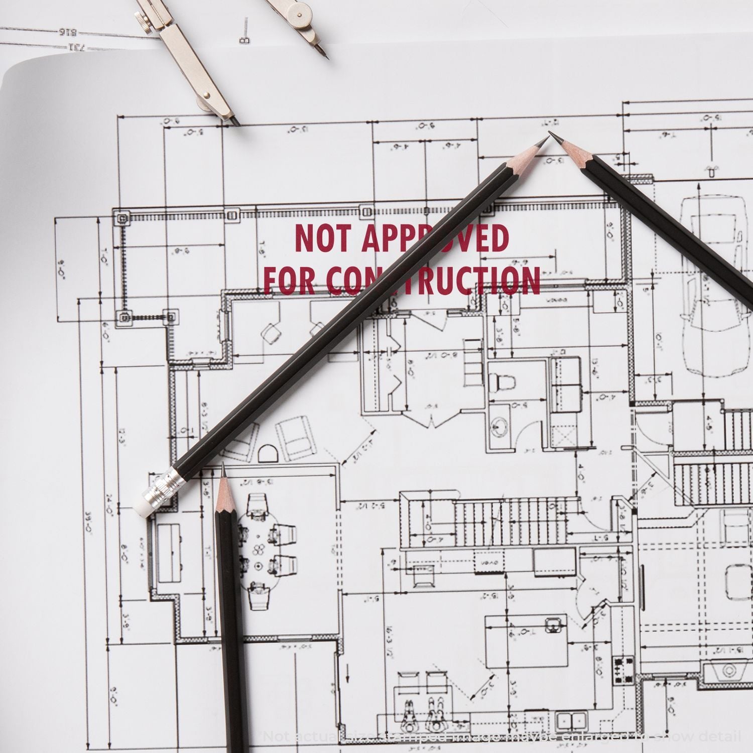 Architectural blueprint with pencils and drafting compass, stamped Not Approved for Construction on building plans.